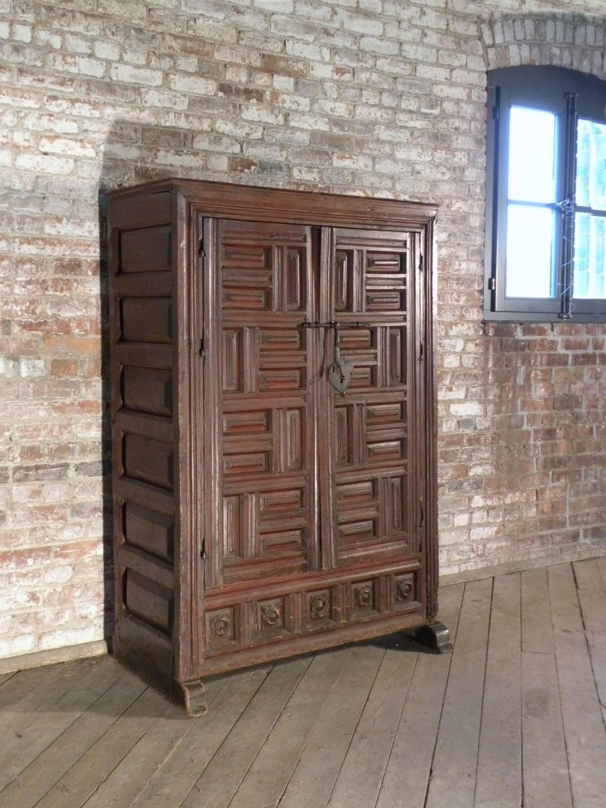 Small two-door wardrobe with an interesting conceptual look.
The geometrically paneled and molded doors with an iron bolted lock opening to an interior featuring a top shelf above a hanging rod. The later green painted interior contrasting