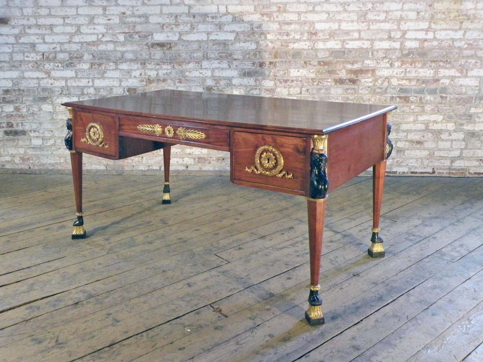 Elegant French Empire bureau-plat or partners desk, The top, inlaid with a center-star-motive and small decorations on each corner, above five drawers, the middle one opening from the front only, the flanking side drawers accessible on both sides,