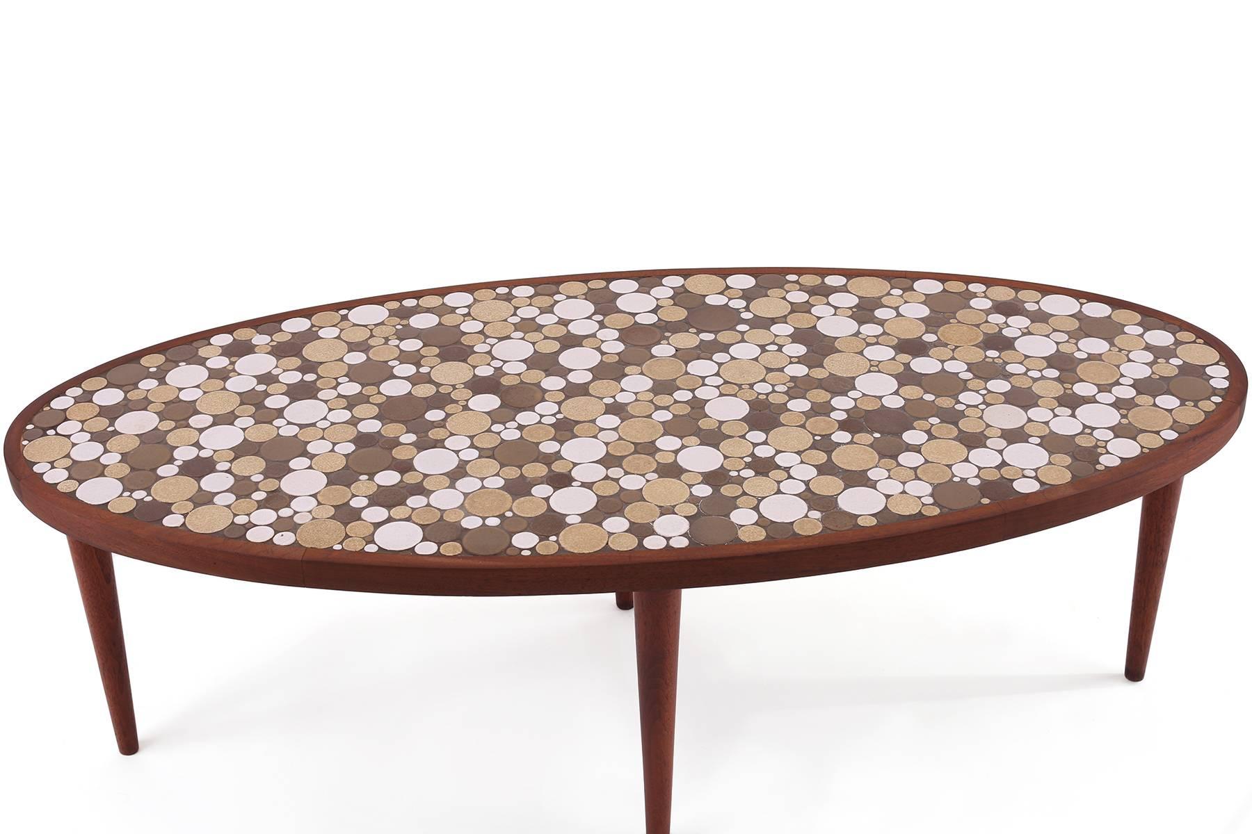 Rare mosaic cocktail table by Jane and Gordon Martz circa late 1950s. This seldom seen example has beautiful inlaid circular tiles with solid walnut legs and trim.
   