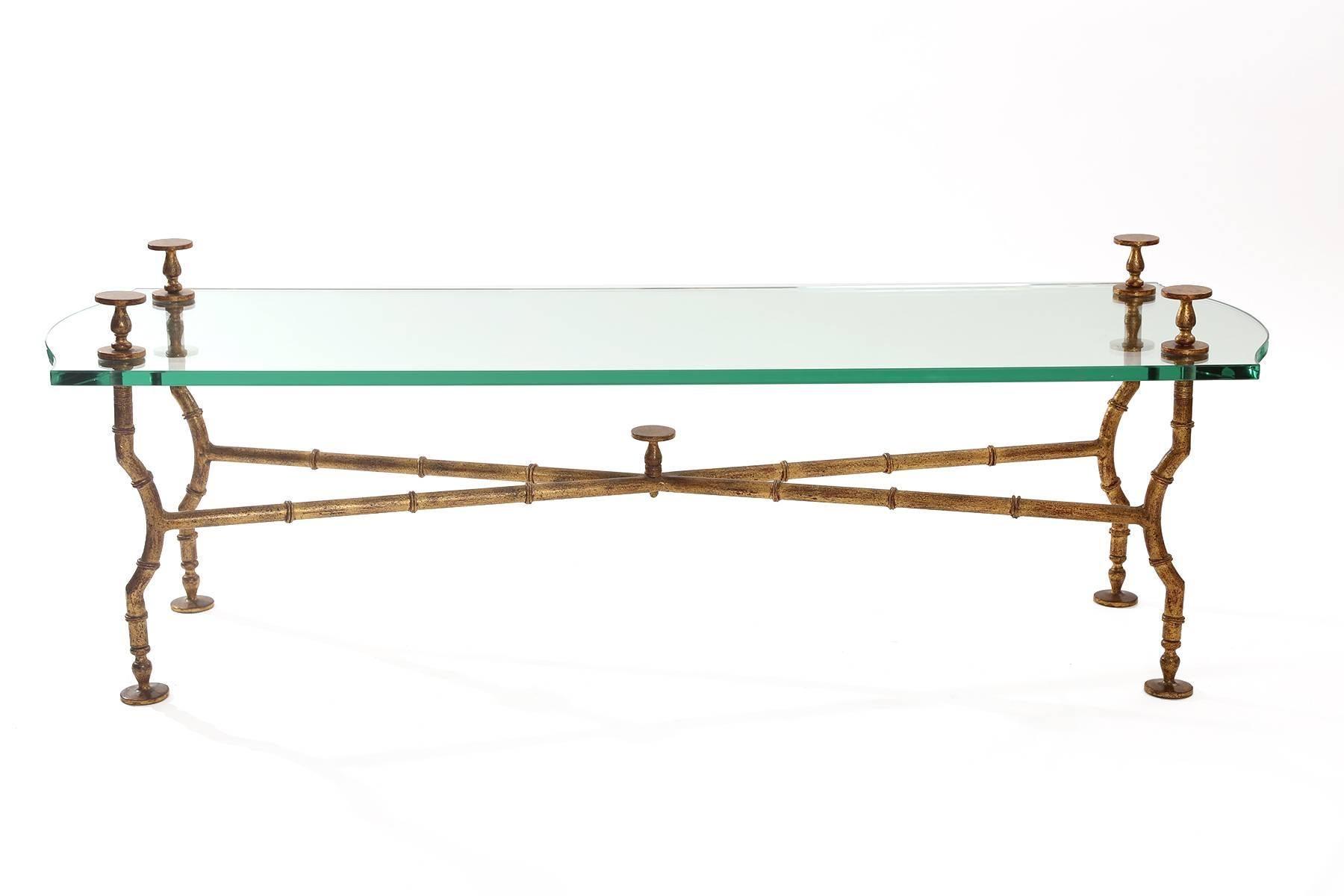 Stunning gold leafed steel and glass cocktail table after Maison Baguès and Giacometti. This all original example has striated legs stretchers and finials and original glass top.

.