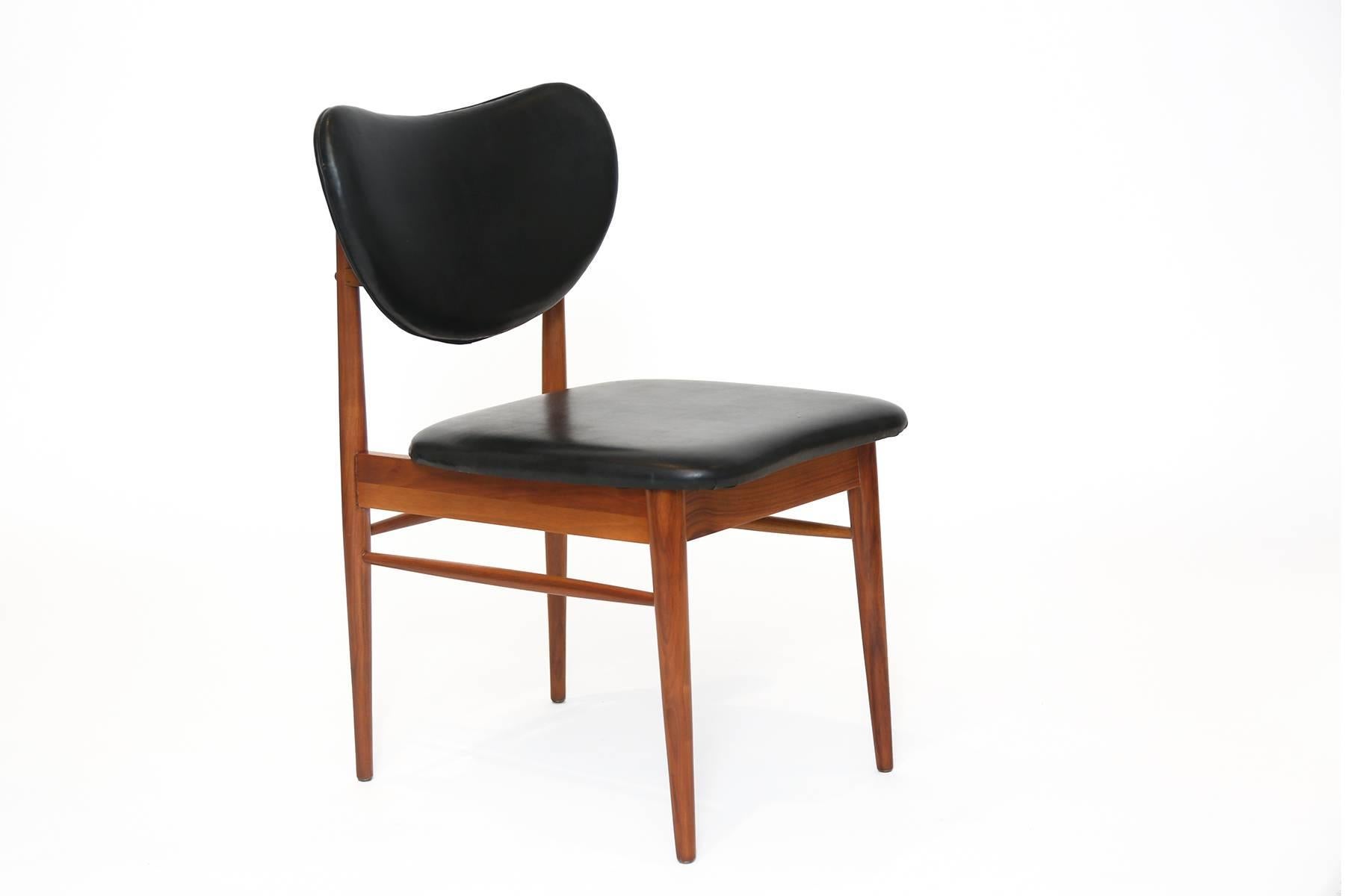 Sculptural walnut and upholstered occasional chair after Finn Juhl. This solid walnut example has tapered solid walnut legs and stretchers and subtly curved back handle. It has been impeccably refinished and retains its original black vinyl