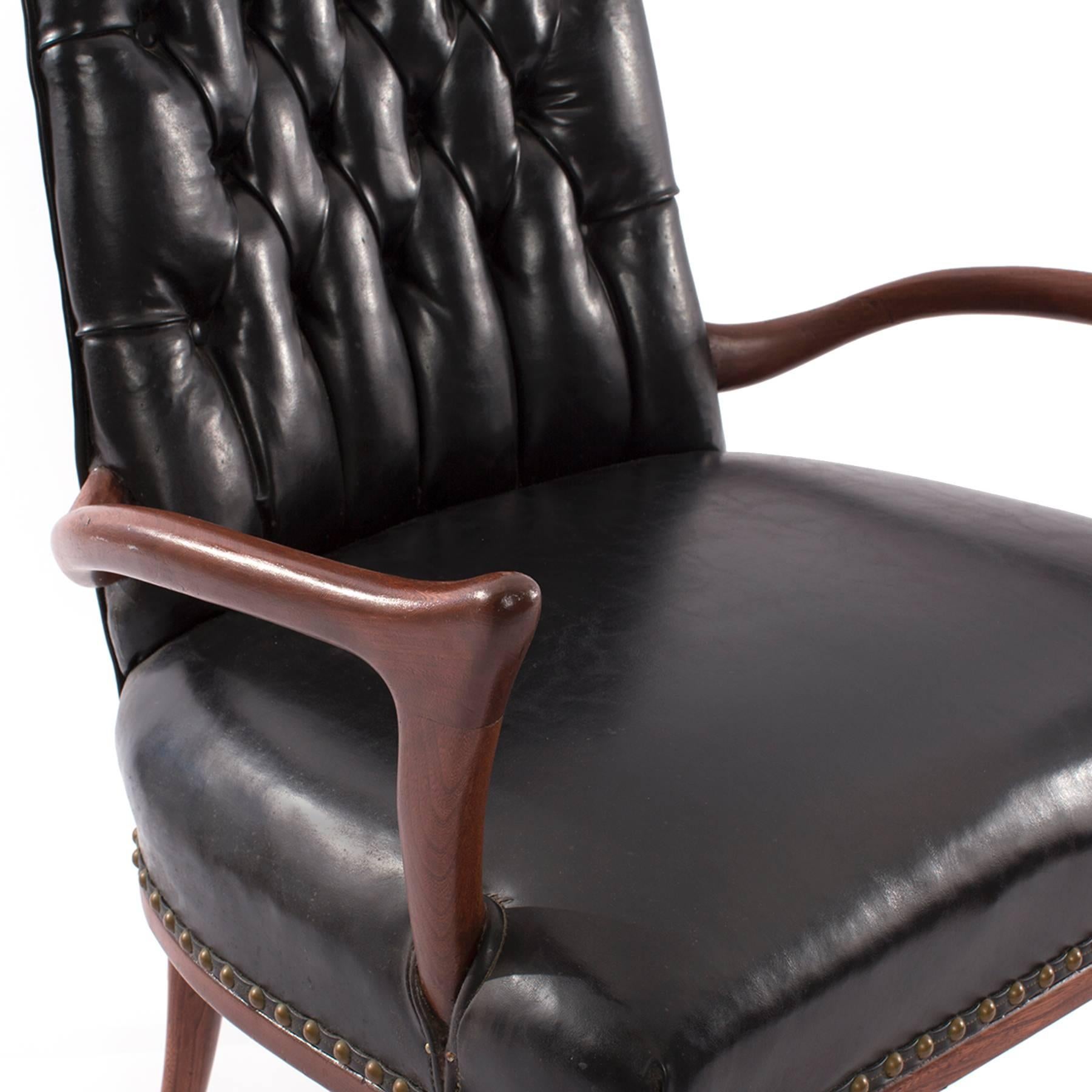 Sculptural mahogany and upholstered arm chair circa late 1950's. This all original example has stunning flared arms and legs and original black vinyl and brass tack upholstery. Can easily be upholstered in a leather or fabric of your choice.