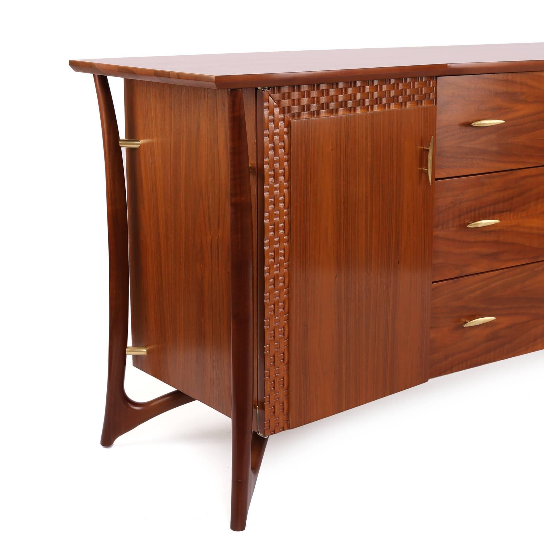 Stunning walnut and brass chest by Piet Hein circa late 1950s. This sculptural example has hand formed solid walnut legs woven wood detailing and patinated brass hardware. It has nine drawers, three large exterior and six interior and has been newly
