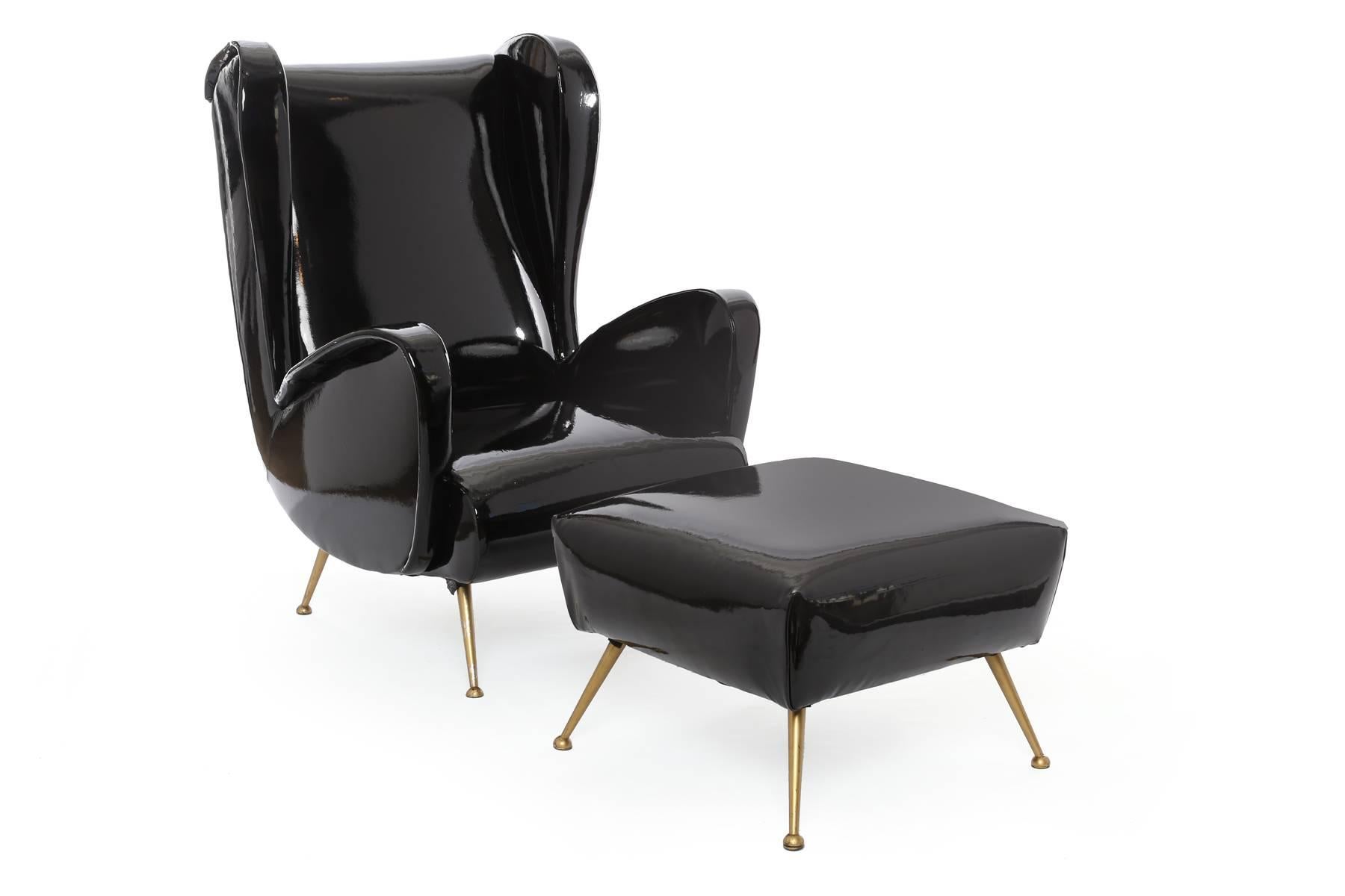 Chic pair of patent leather and brass Italian armchairs, circa late 1950s. These lovely examples are upholstered in a black patent leather and have sculptural arms and sides with splayed brass legs. Ottoman measures: 14.5