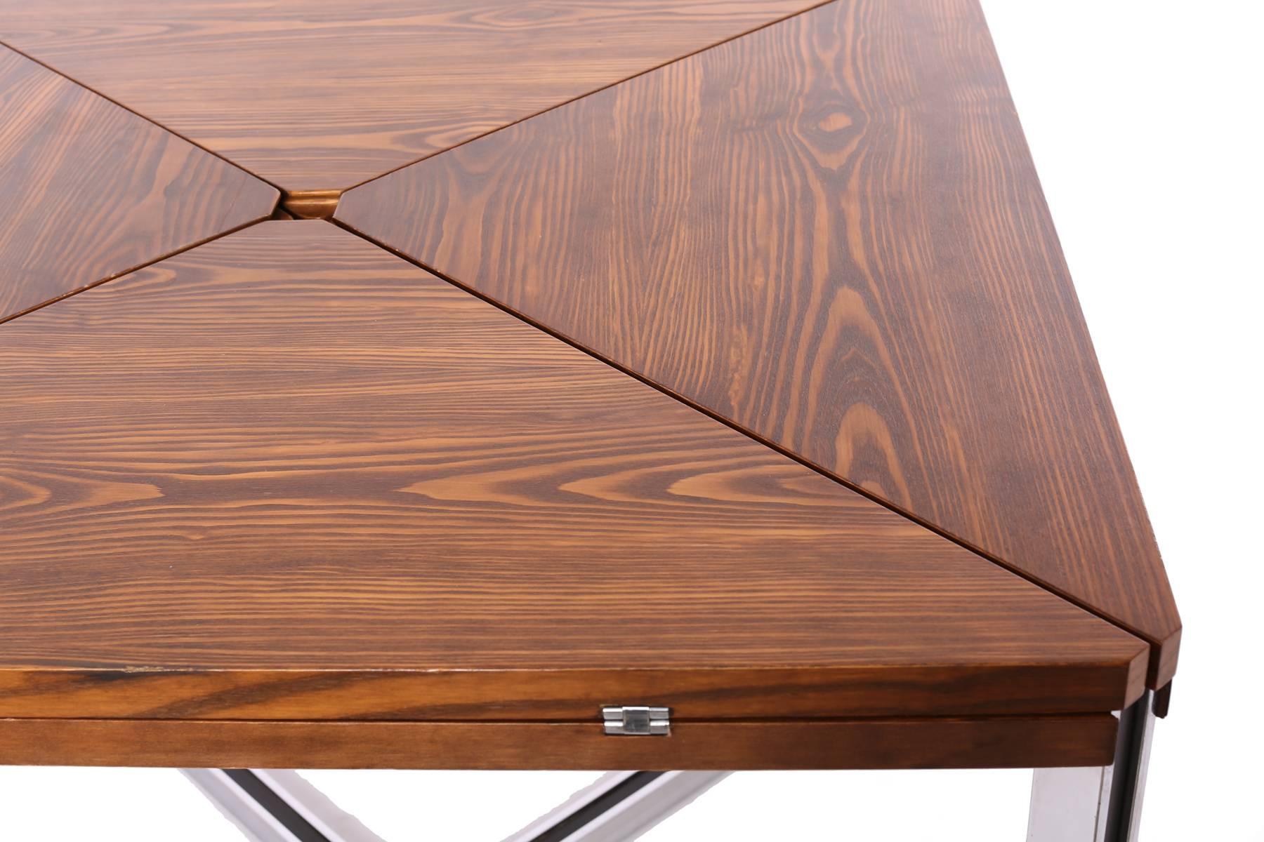 Expandable wenge and chrome dining table by Dyrlund, circa early 1970s. This seldom seen example has a book matched beautifully grained wenge top. Each side of the dining table folds over almost origami style to reveal inset steel and can be used in