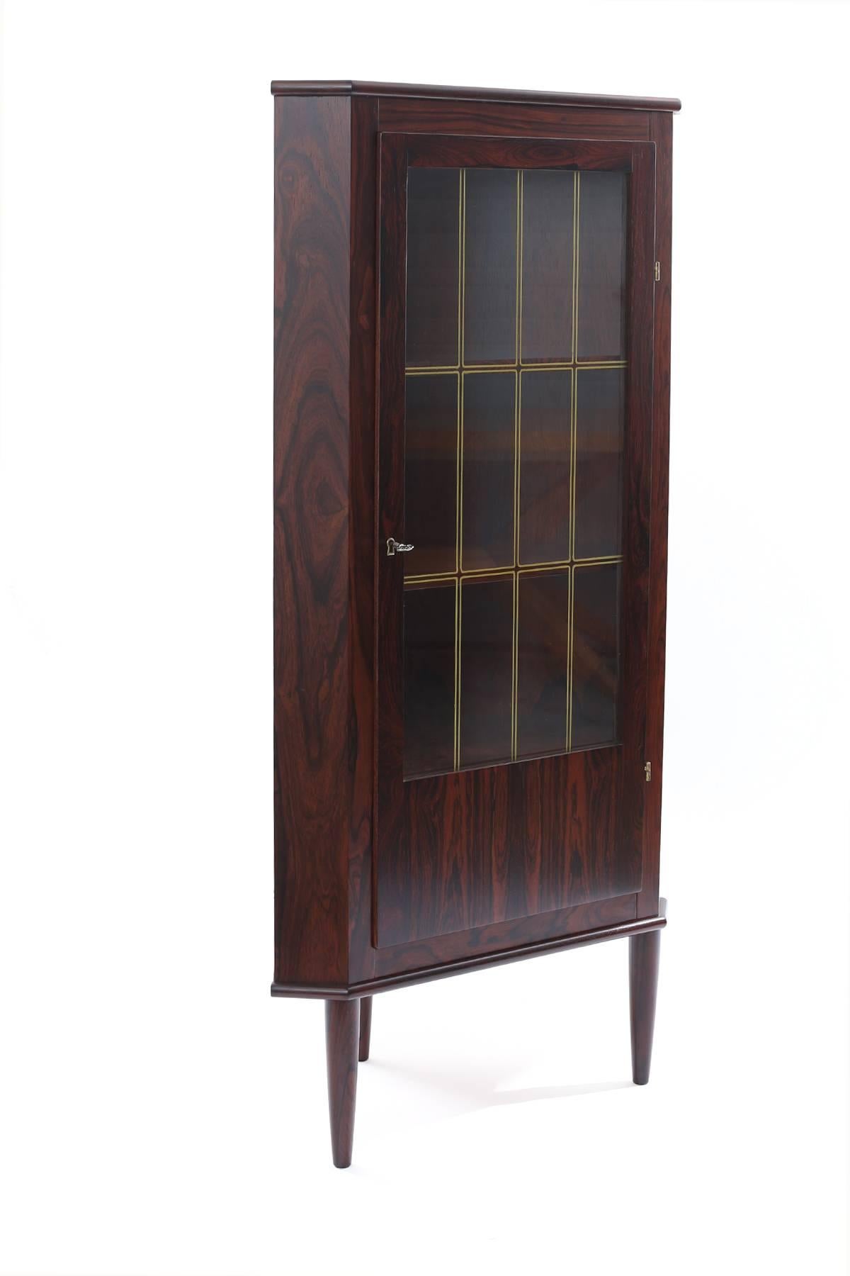 Brazilian rosewood and glass corner chest from Denmark, circa mid-1960s. This example has a beautifully grained rosewood case, inset glass in the door and three interior shelves. The tapered legs are solid rosewood. This has been newly and