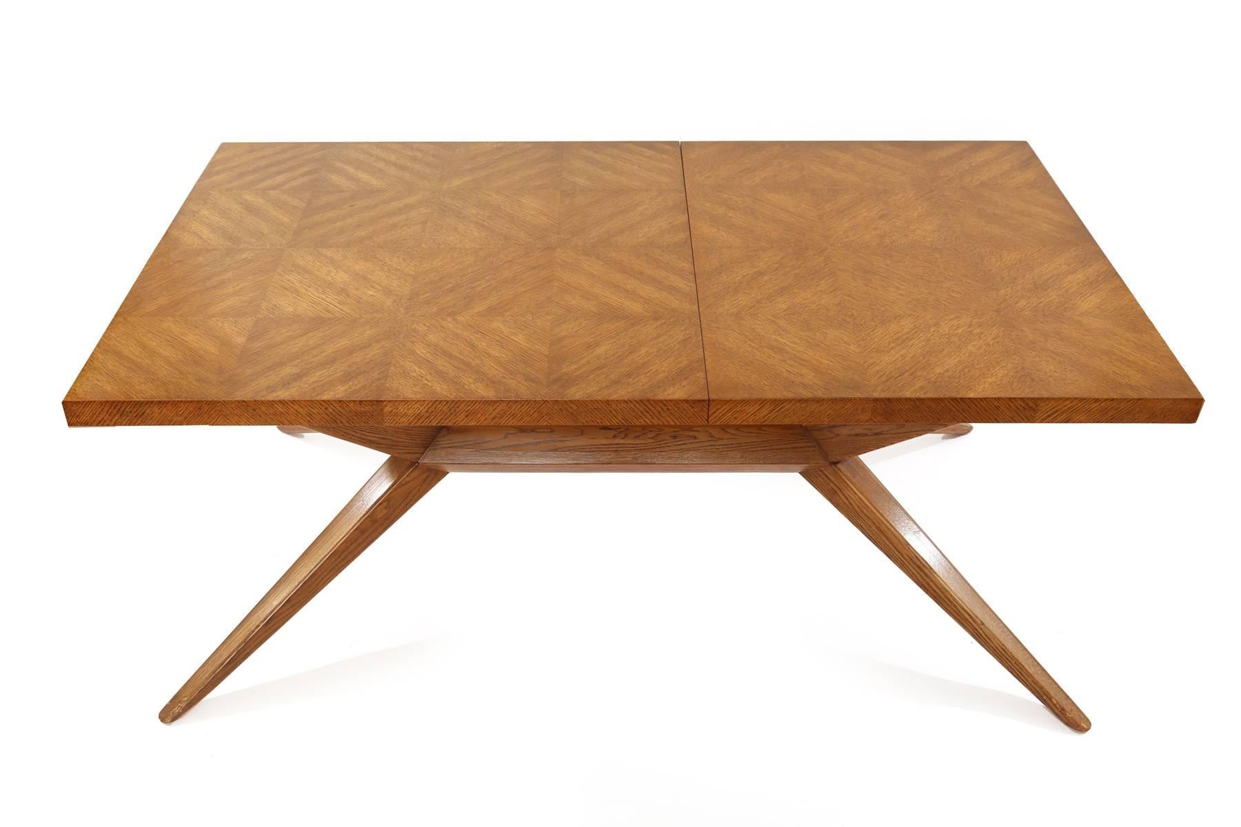 Harold Schwartz for Romweber sculptural dining table, circa early 1950s. This all original example has a stunning book matched oak top with subtly tapered splayed legs and divided drawers on either end for silverware. Without the two leaves the