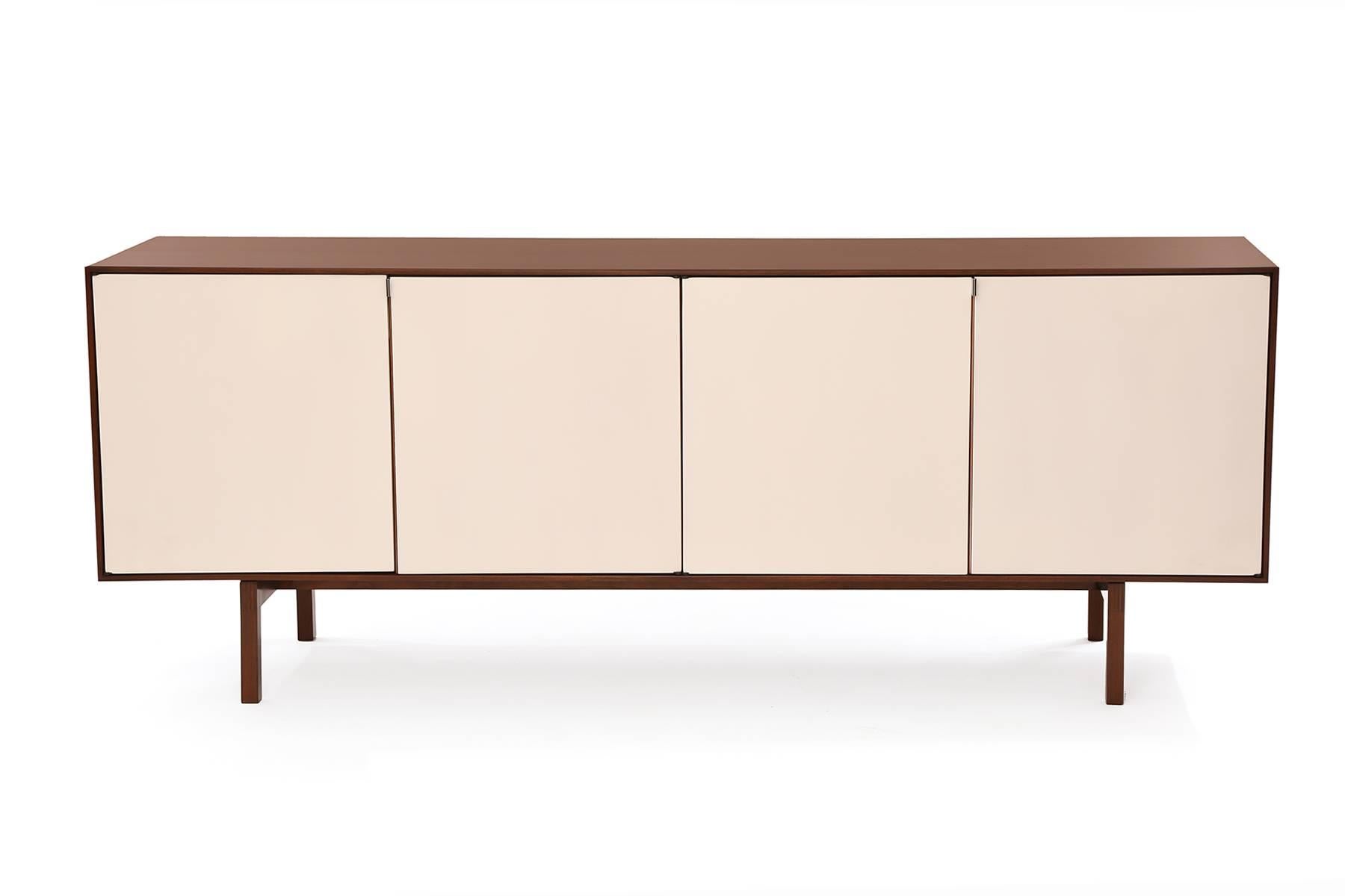 Florence Knoll for Knoll sideboard or credenza circa early 1950s. This stunning example has four white lacquered doors, walnut case and steel door pulls. The oak interior has two slatted drawers and adjustable shelves. It has been newly and