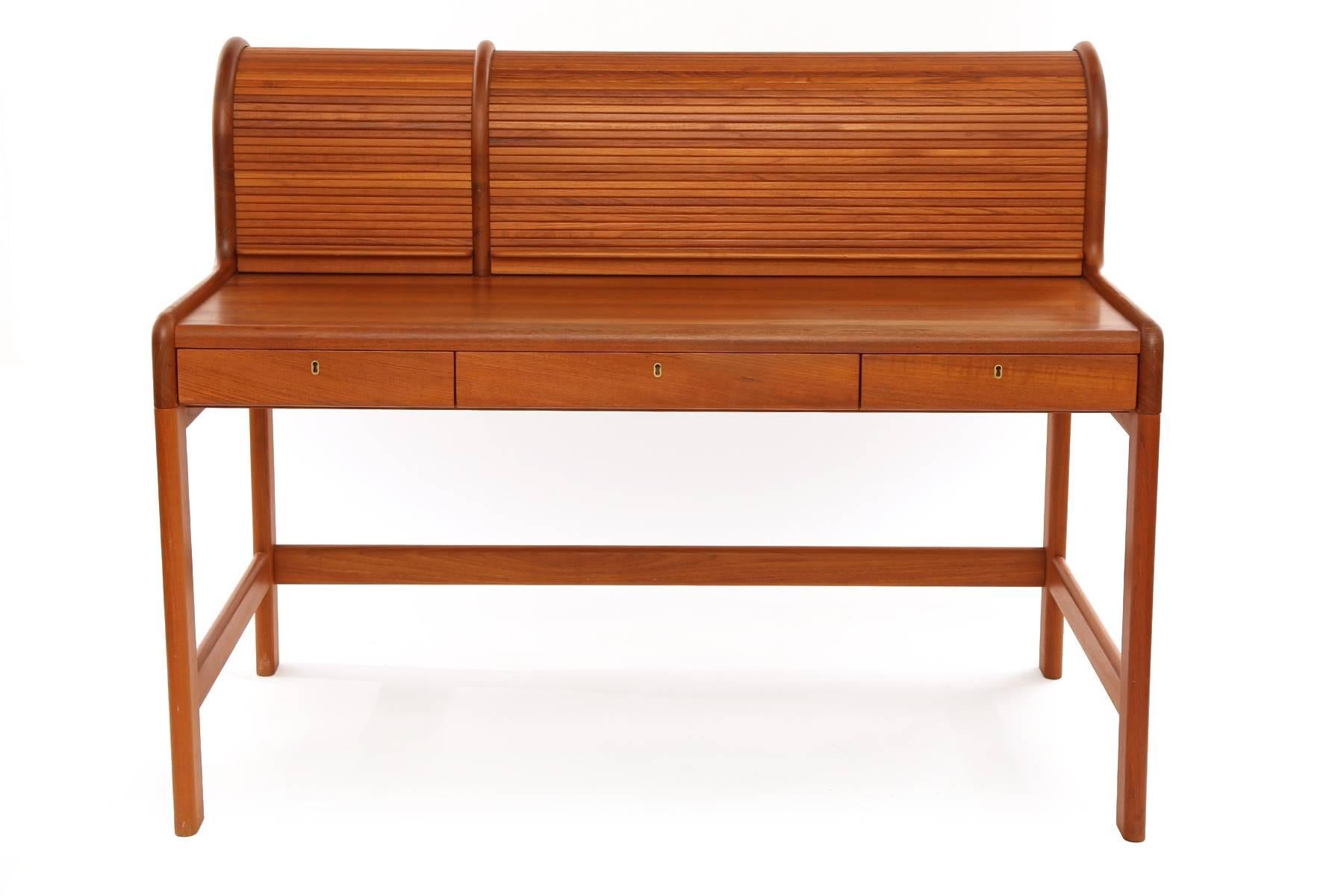 Solid teak roll top desk from Denmark, circa early 1970s. This all original example has two roll tops with interior shelves and three drawers. Writing surface height is 28 3/4