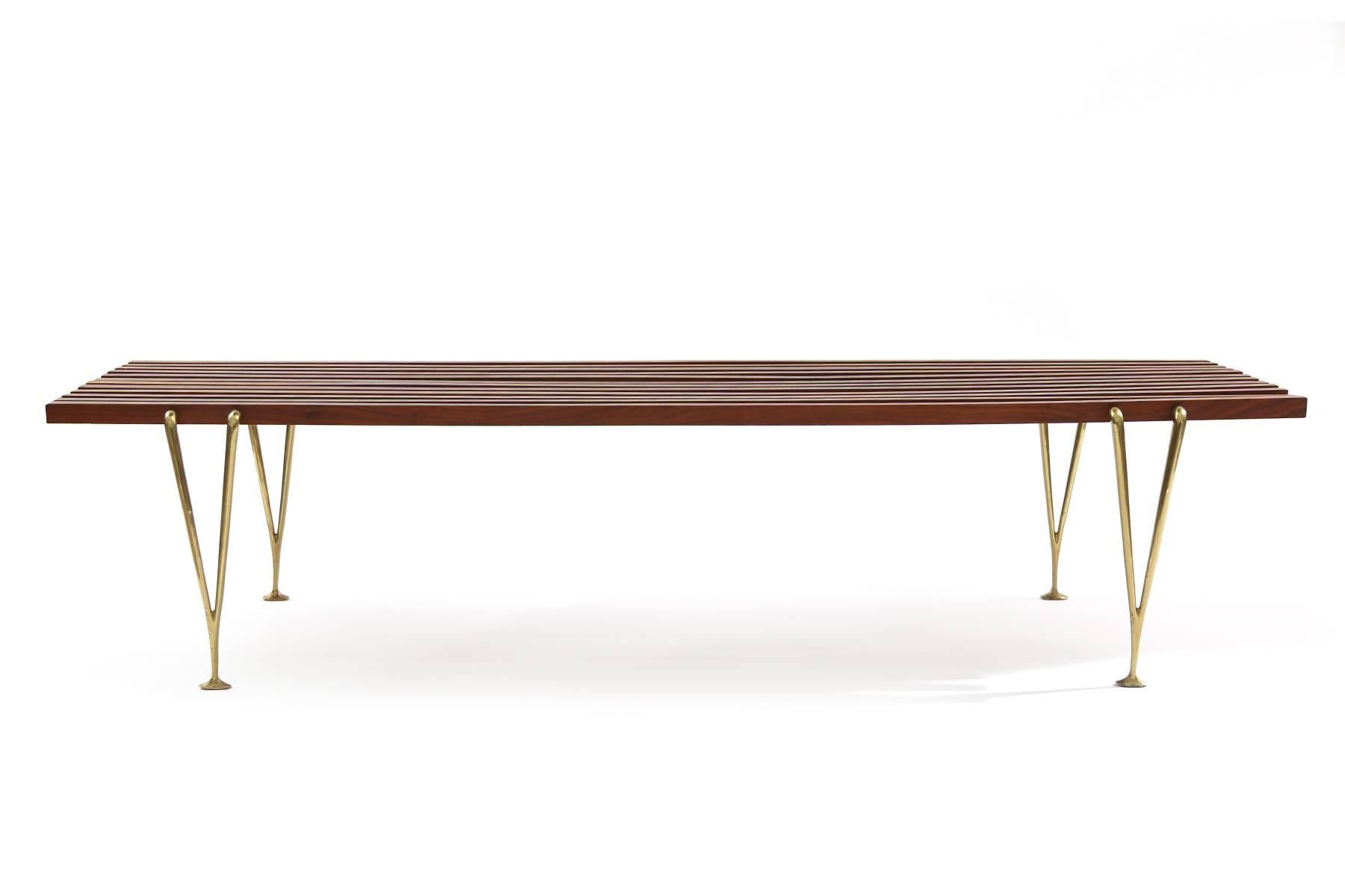 Hugh Acton walnut and brass bench, circa early 1970s. This all original example has solid walnut slats held up by Acton’s iconic sculptural brass legs. Some patina to the brass legs.
    