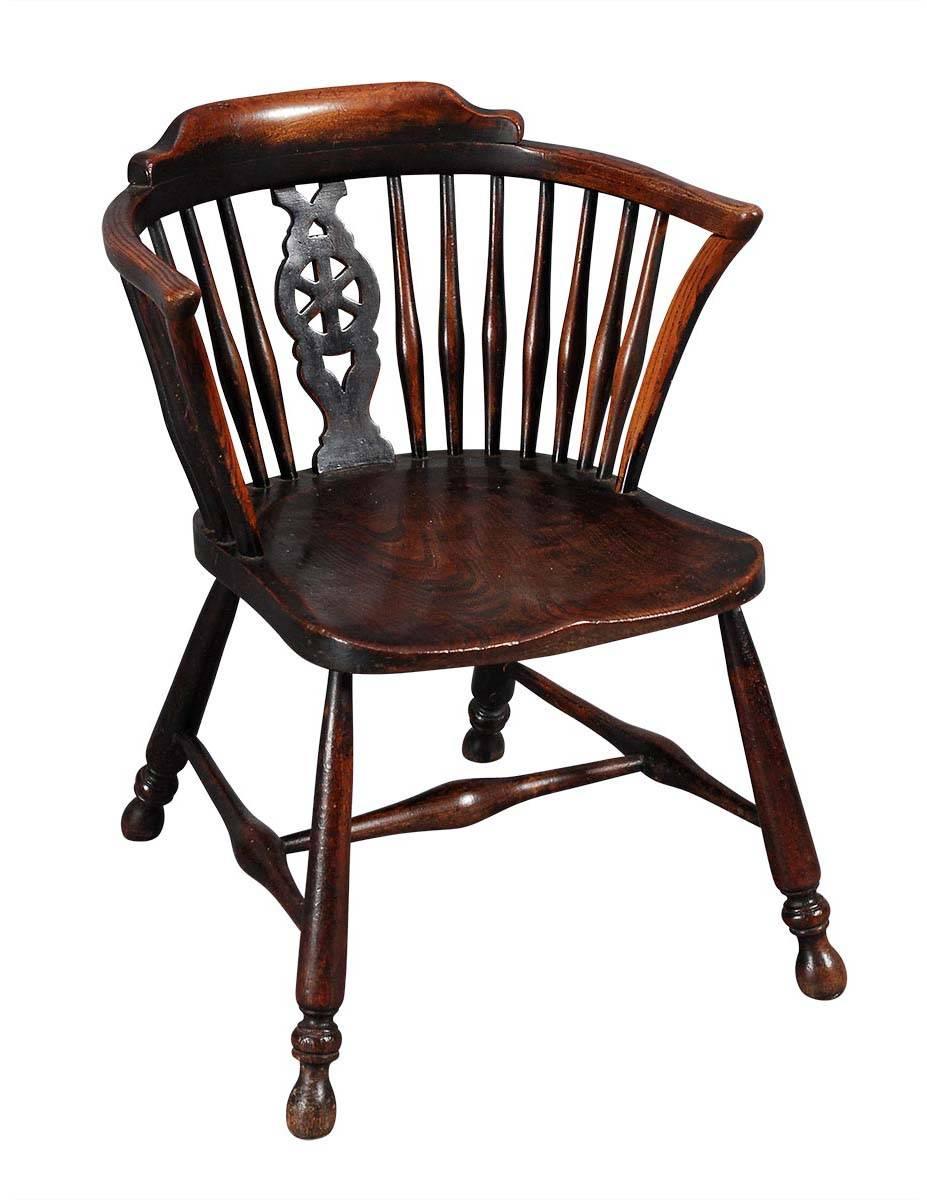 A child's windsor armchair with pierced wheel-back splat. The shaped elm seat is supported by legs ending in turned feet. Terrific color and patina.