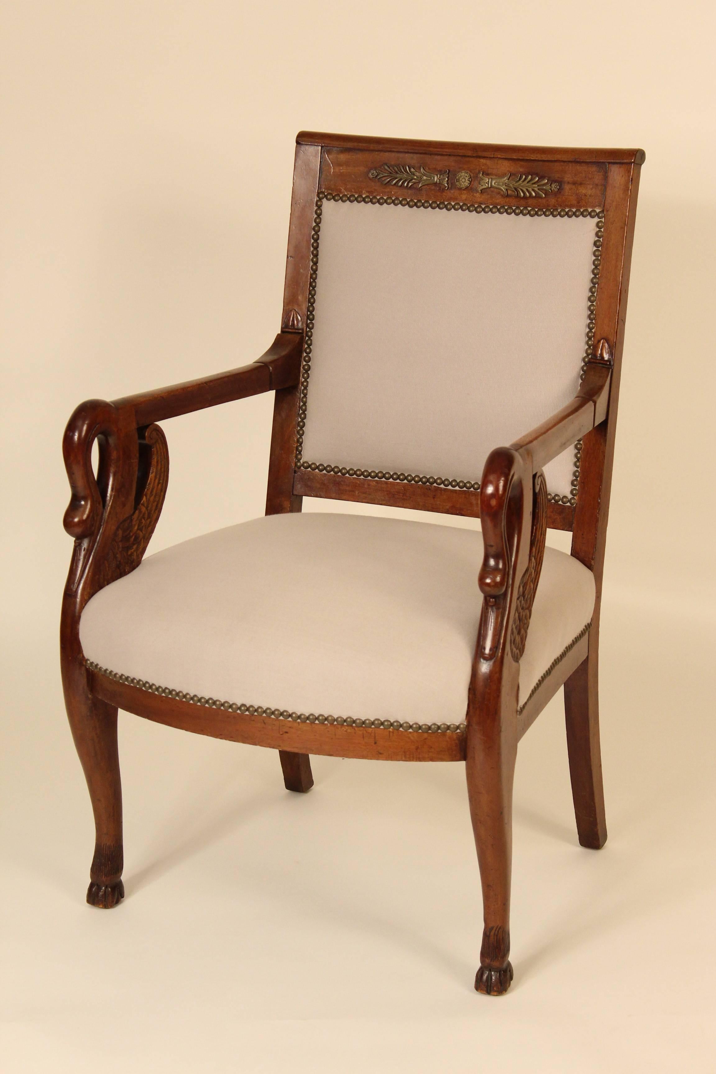 Pair of mahogany Empire style armchairs with swan carved arm supports and bronze mounts on crest rails, circa 1910. Both chairs were recently upholstered.