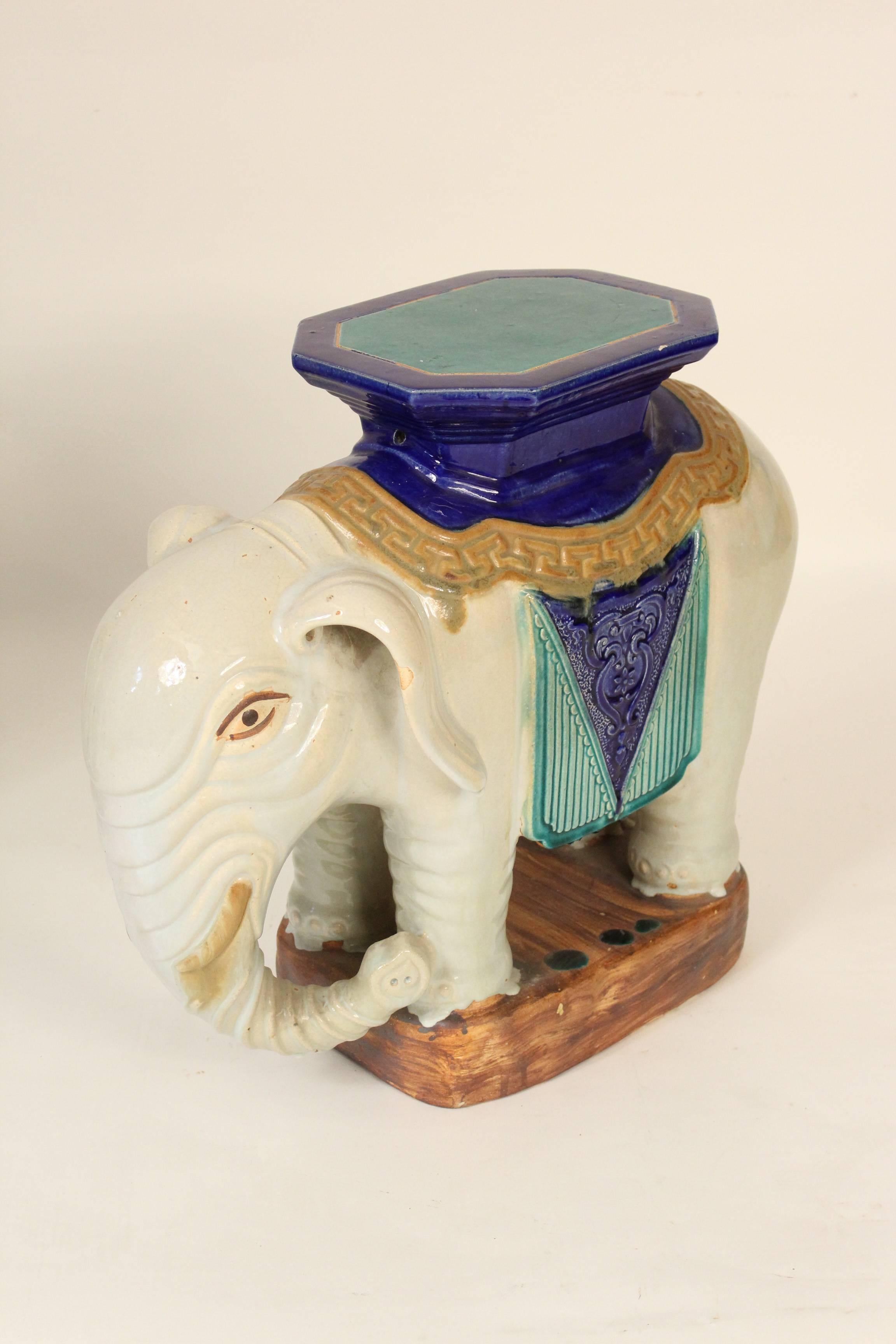 Pair of Chinese stoneware polychrome decorated elephant form occasional tables, circa 1990. These elephant tables are a very fun colorful pair of tables that could be used either indoors or outdoors. The table tops measures 11.5