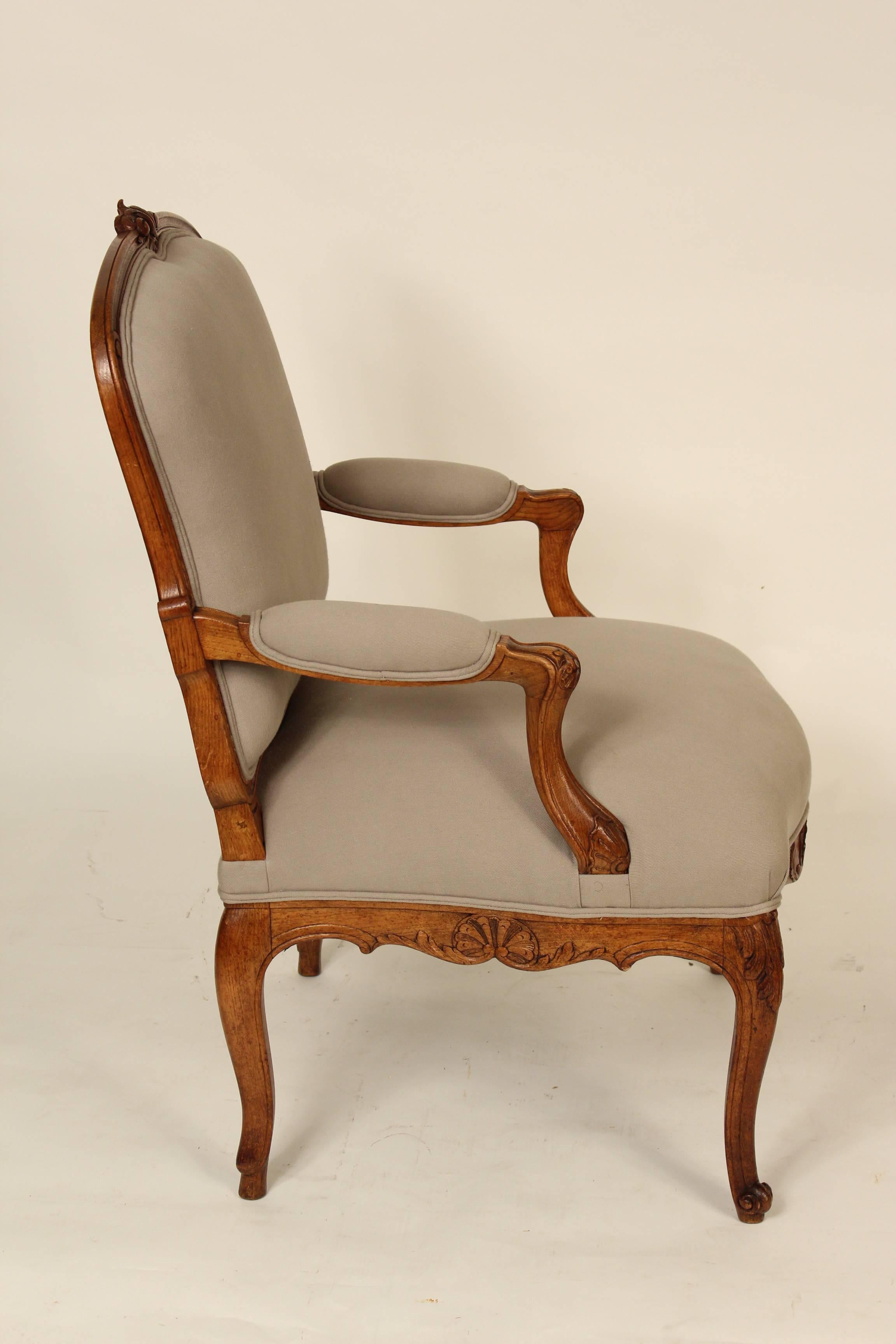 Pair of Louis XV style beech and oak open armchairs, circa 1920. These chairs were recently reupholstered and they have understated carving.