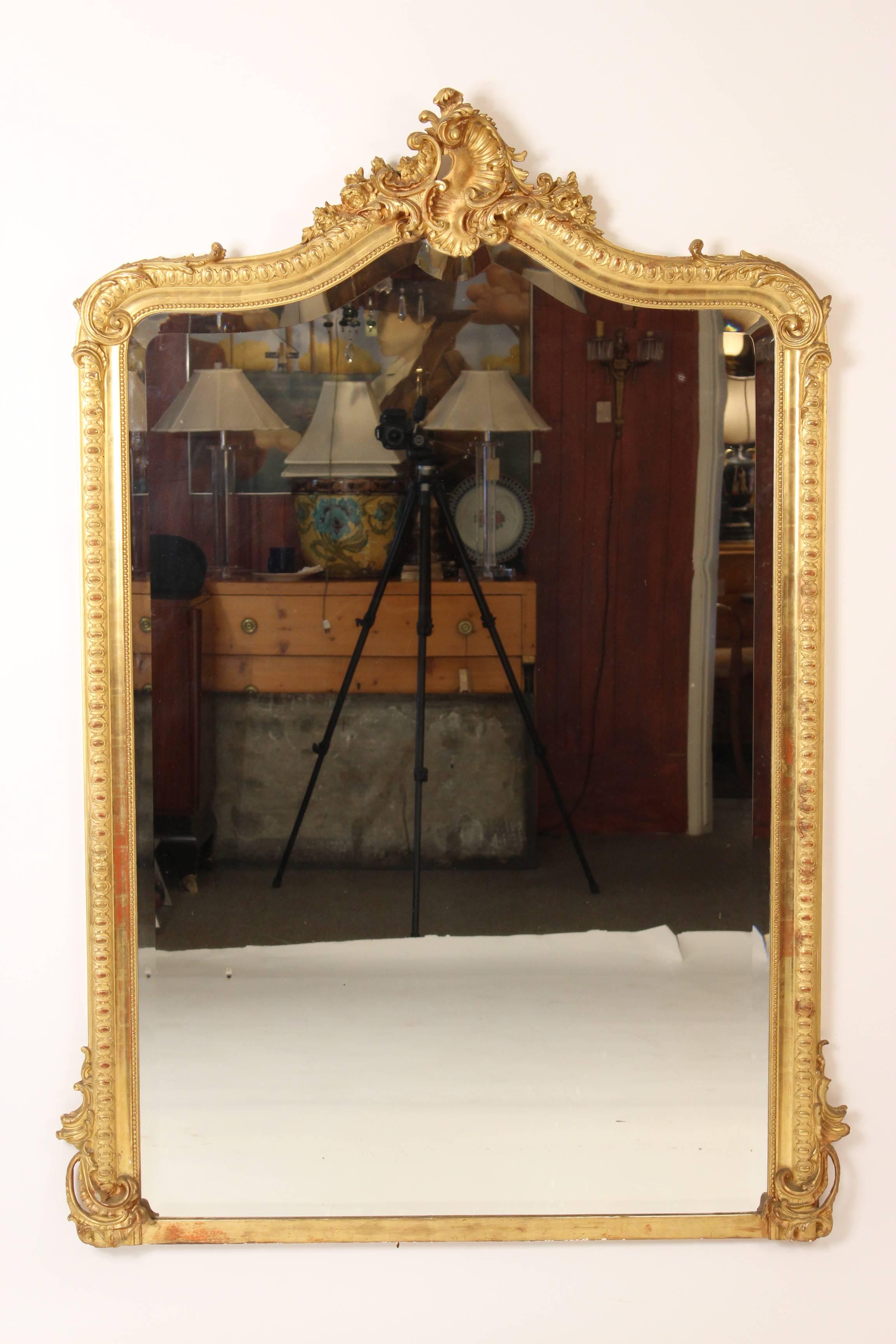 Louis XV style giltwood mirror, circa 1900. This mirror has fine quality original gold leaf. The glass is original, beveled and shows signs of aging.