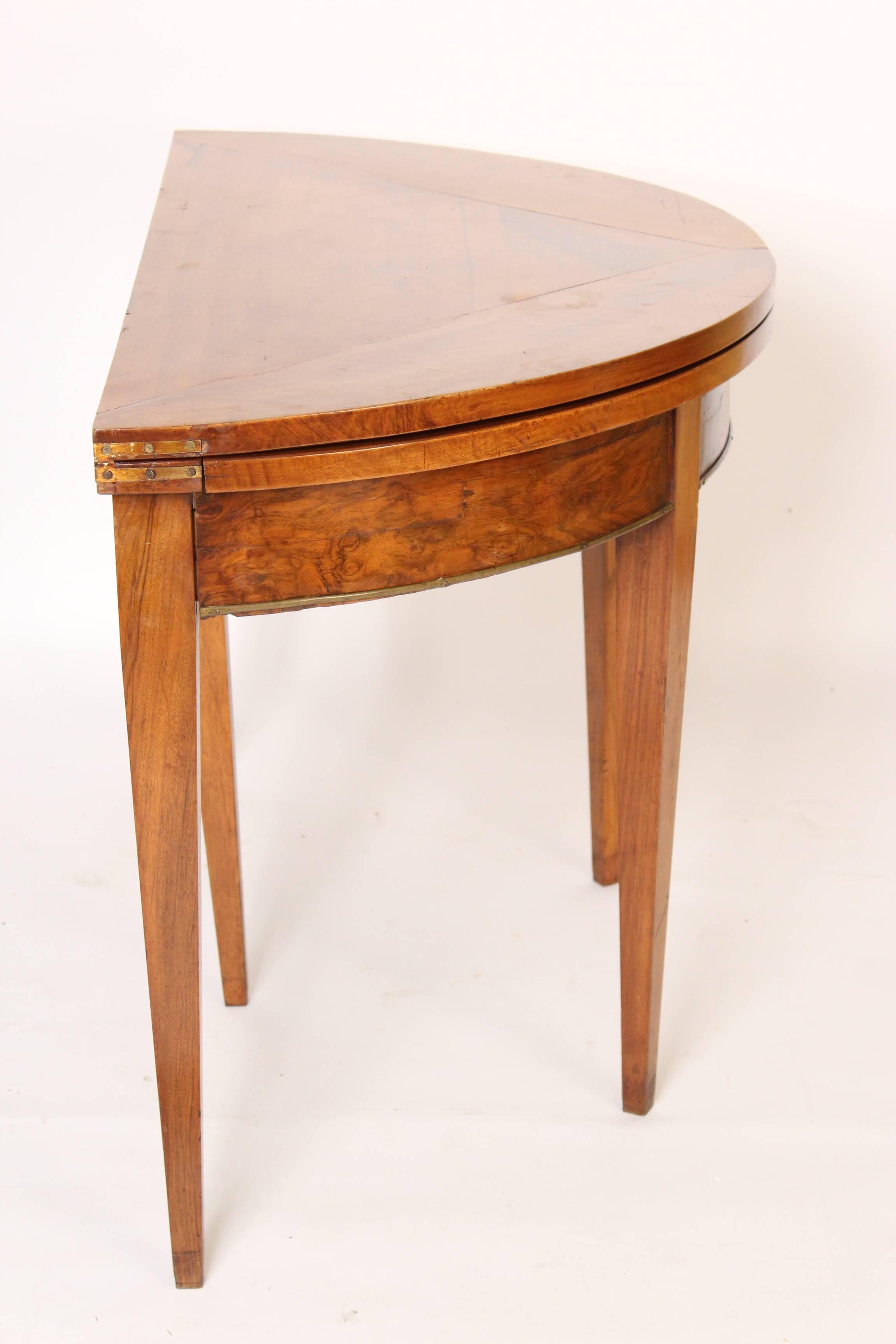 Directoire walnut and burl walnut demilune shaped games table, circa 1800. The lower apron has brass molding. The walnut has very nice color. The diameter when opened is 47".