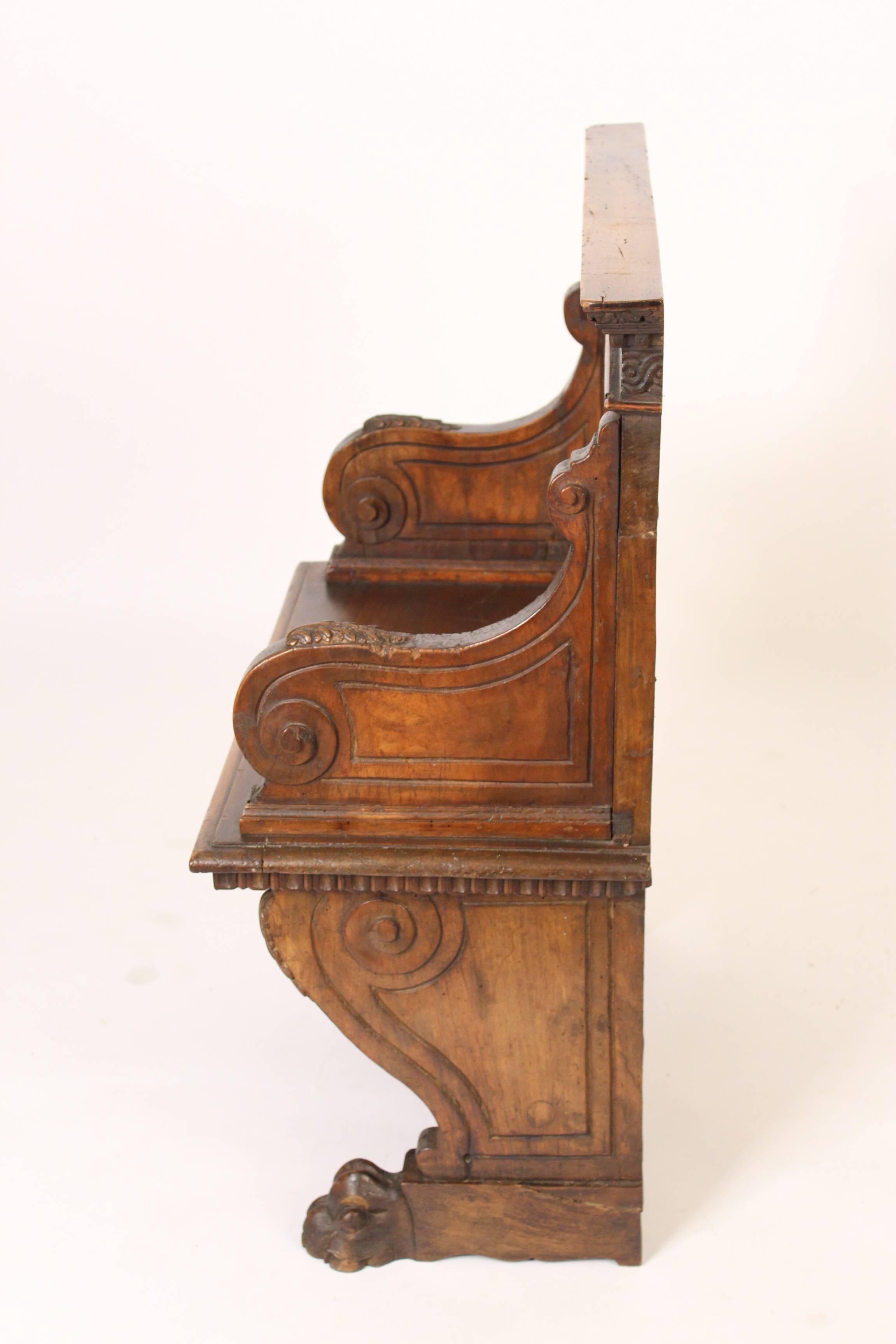 Baroque style walnut bench, 19th century. The back having dental molding
and carved guilloche design with Romanesque arches, voluted arms and paw feet. This bench has excellent original patina.