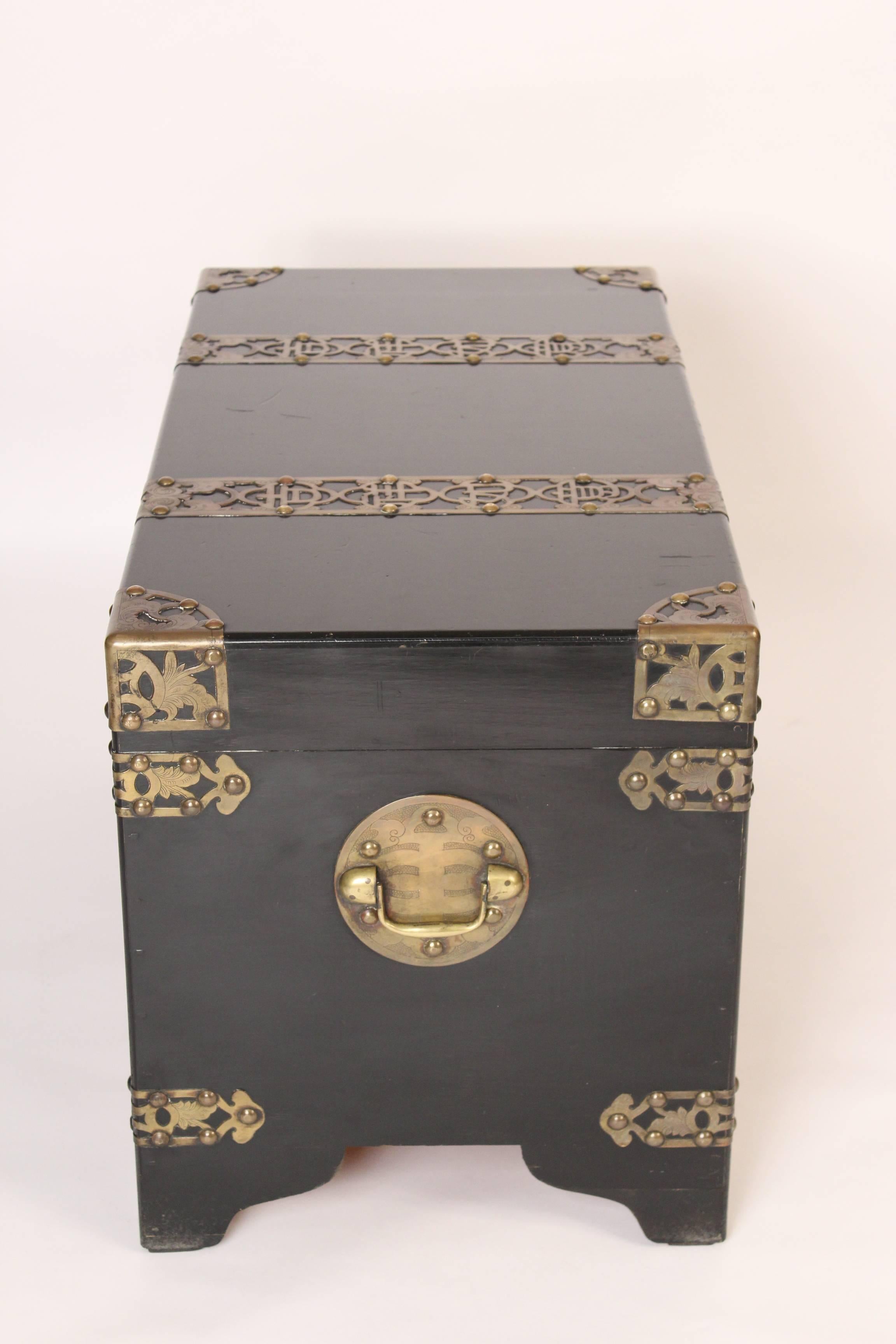 Chinese style black lacquer trunk with brass mounts, mid-20th century. This trunk has bold and interesting brass mounts.