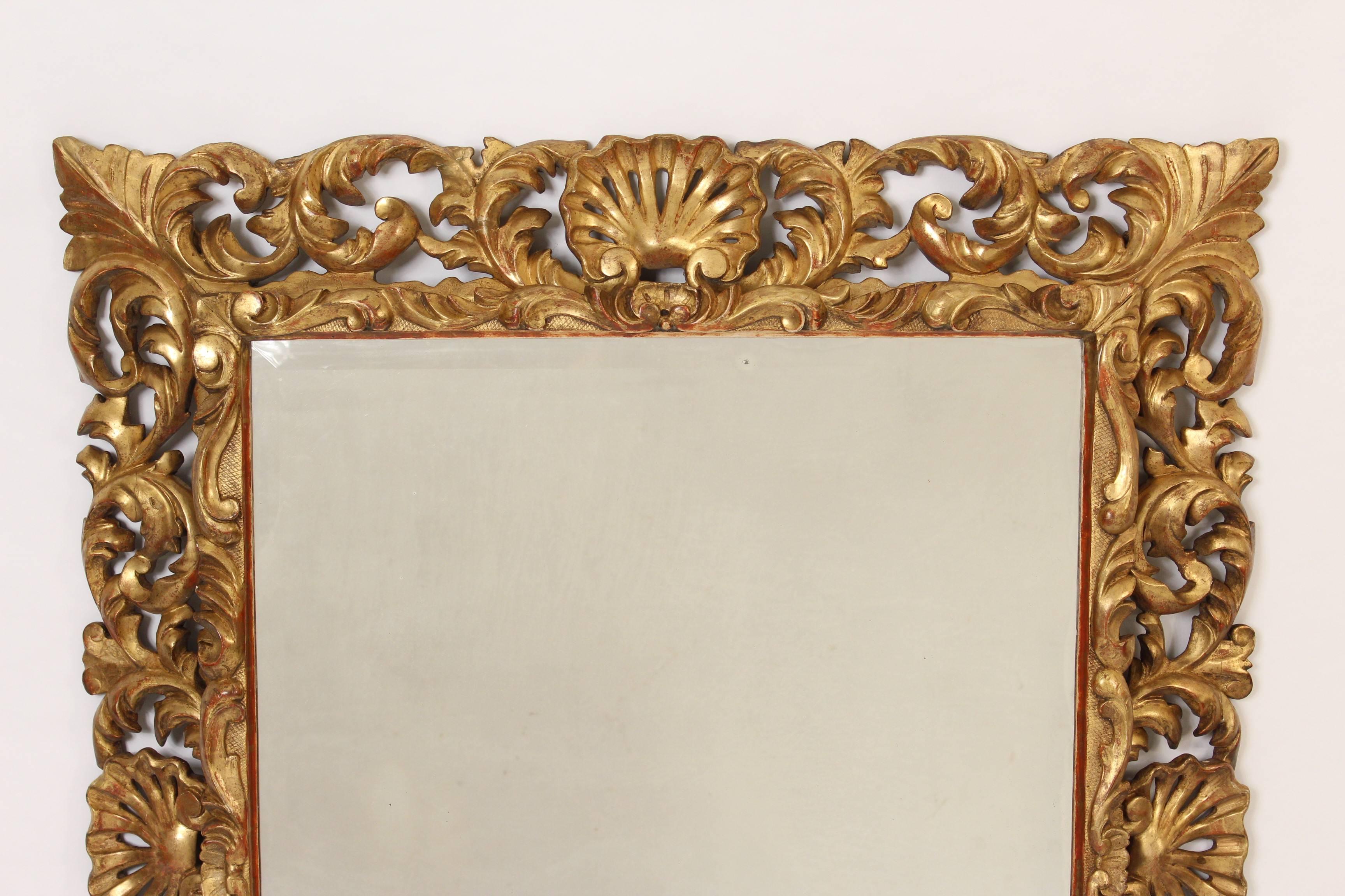 Antique Baroque style giltwood mirror having deep carved shell and foliate carvings with a bevelled glass mirror, 19th century.