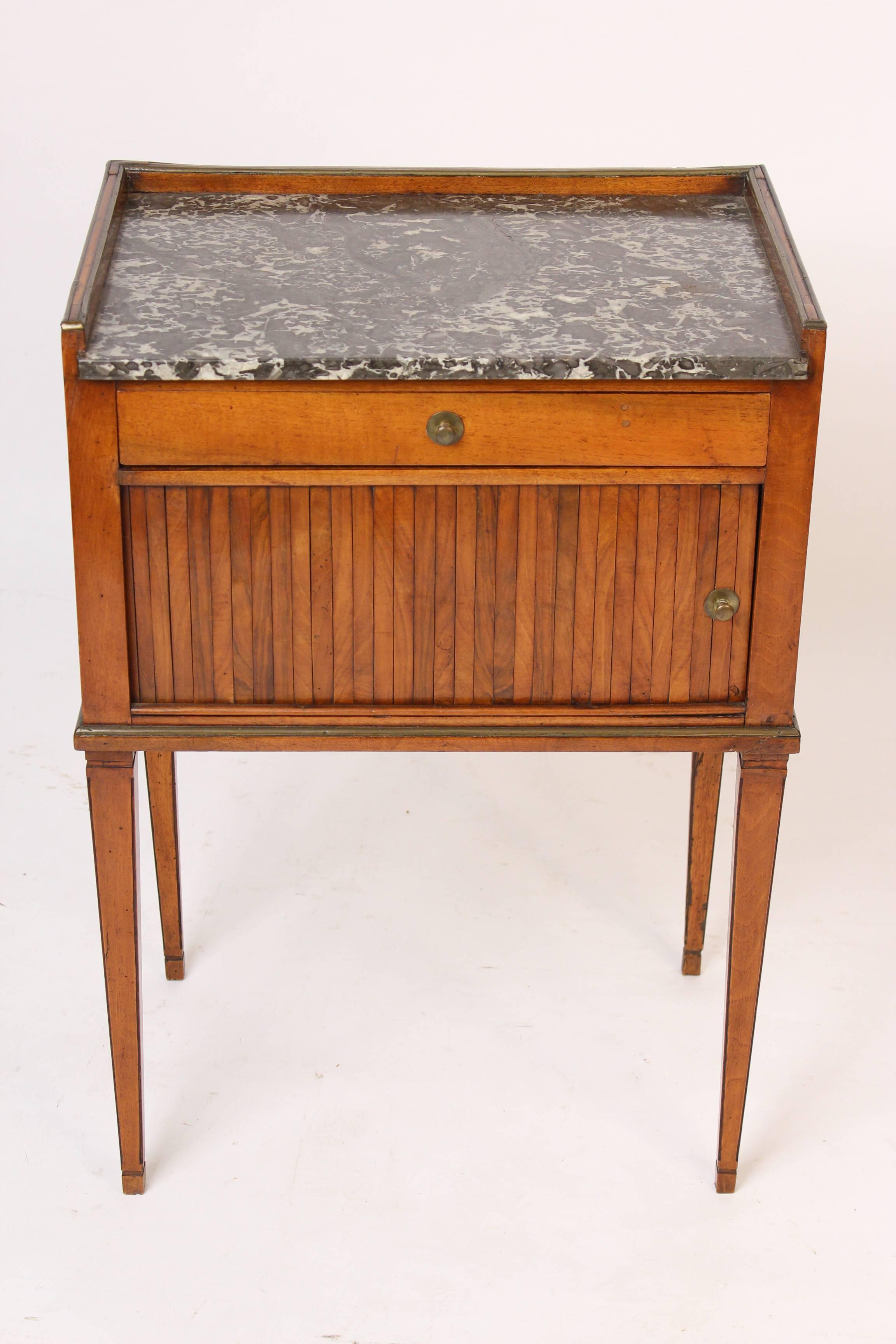Directoire walnut and mahogany occasional table with a sliding tambour door, brass moldings and a marble top, early 19th century. Nice old patina.