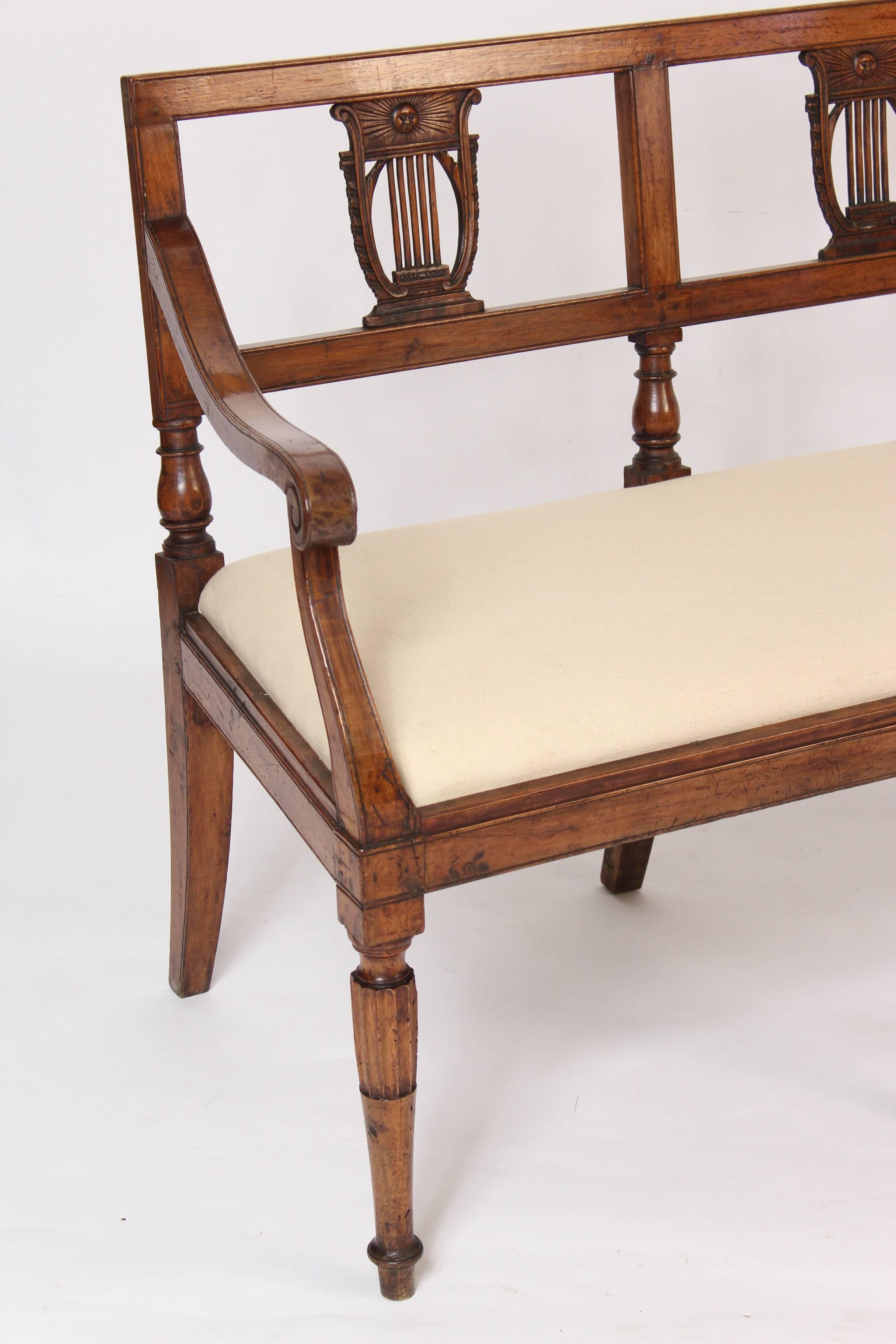 Louis XVI walnut settee with lyre shaped back splats, partially fluted and turned front legs, linen upholstery, pegged construction and an excellent old patina, made circa 1800. 