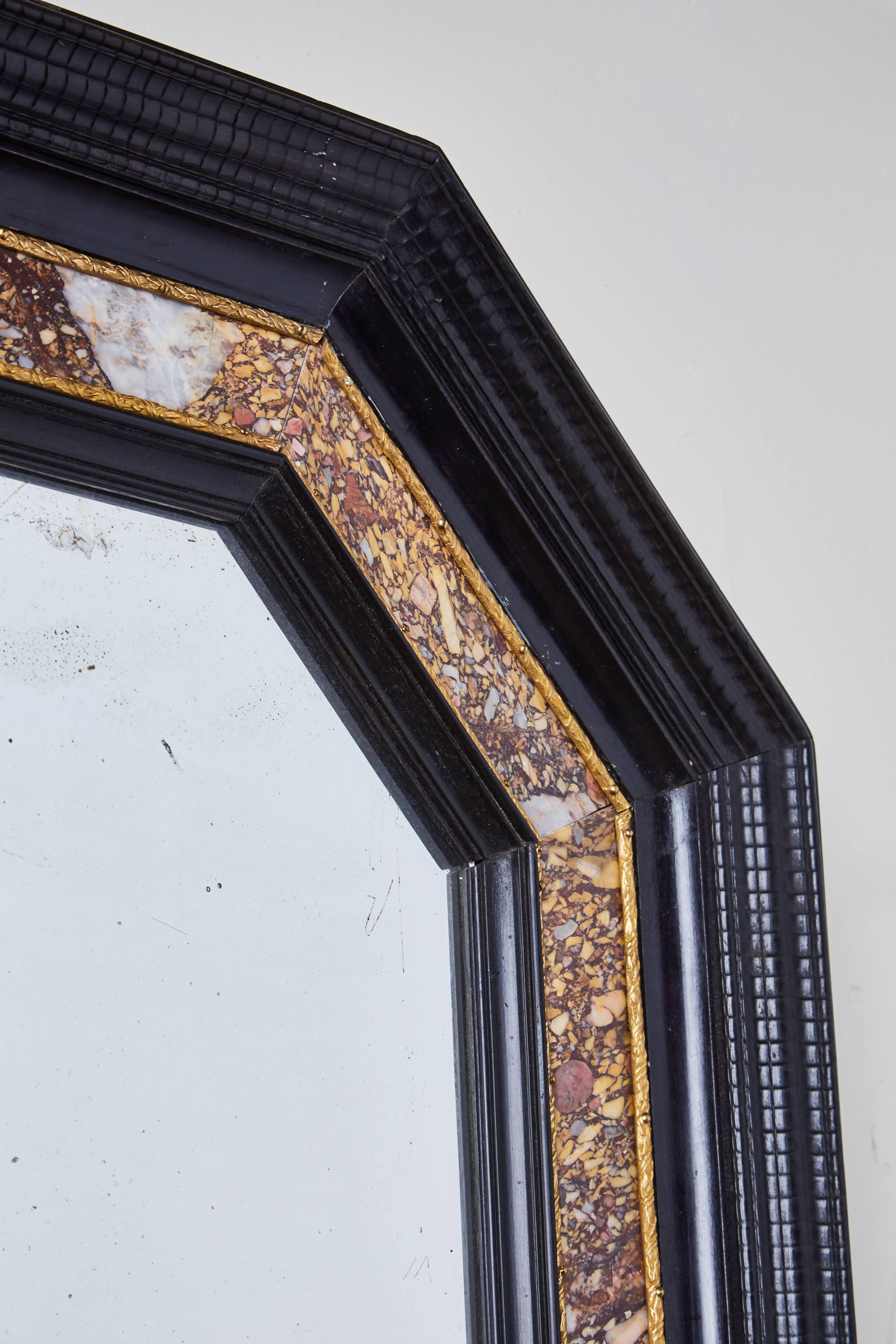 Two, ebonized wood, parcel-gilt, Italian octagonal frames with generous marble inlay. Both inset with mercury glass mirrors and surmounted by gilt bronze rings for hanging.