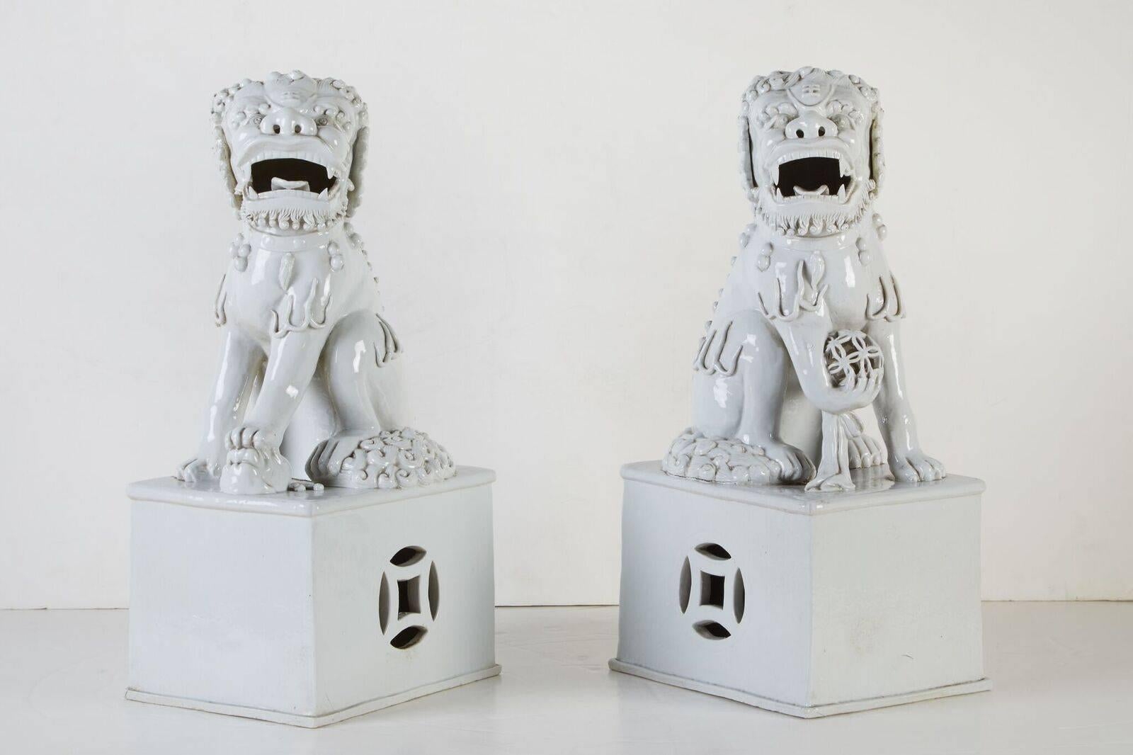 Pair of left and right, 1920s, blanc de chine foo dogs on matching, raised pedestals.