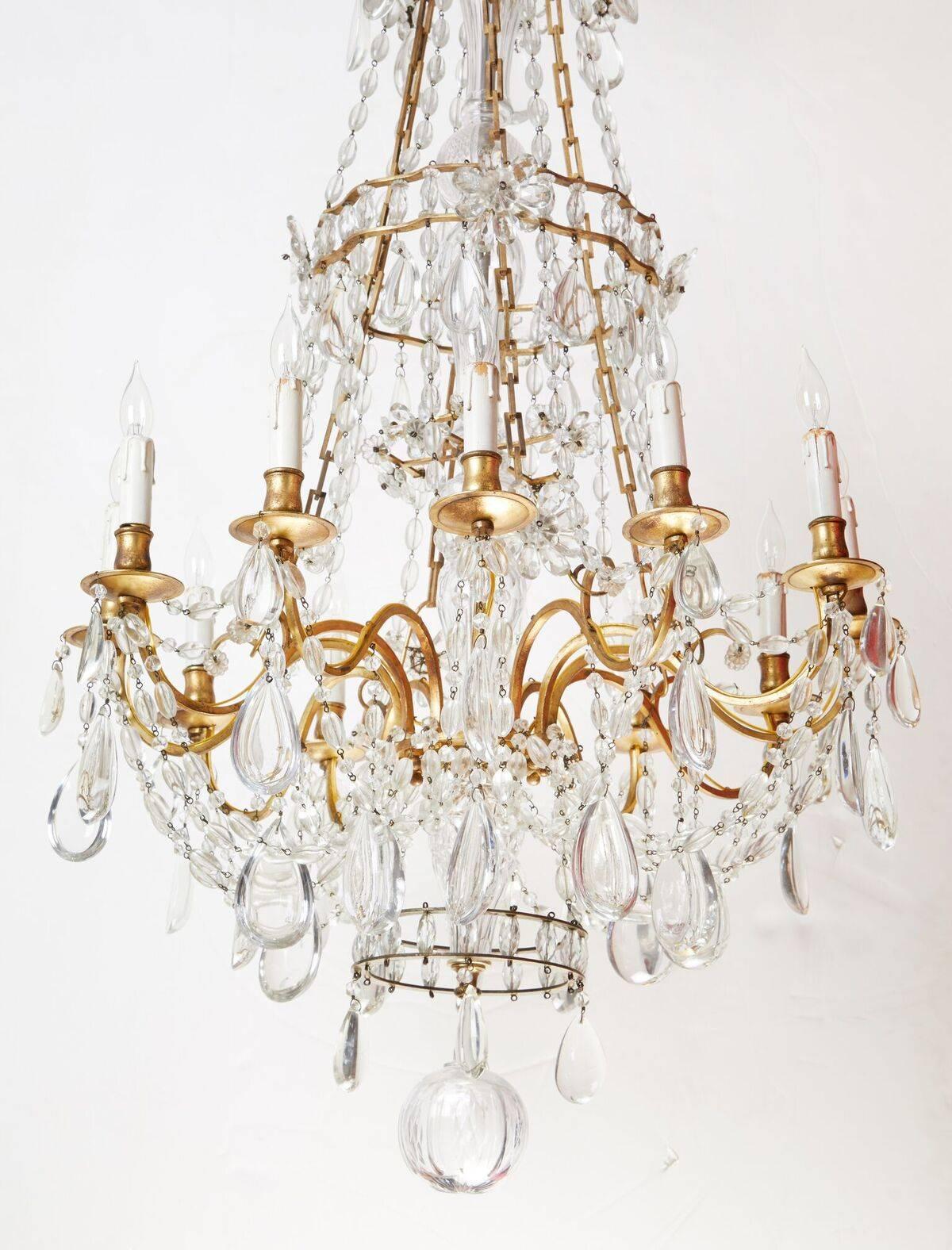 An elegant pair of mated, circa 1900, French, gilt bronze, twelve-arm chandelier with generous layers of crystal swags and large drops.