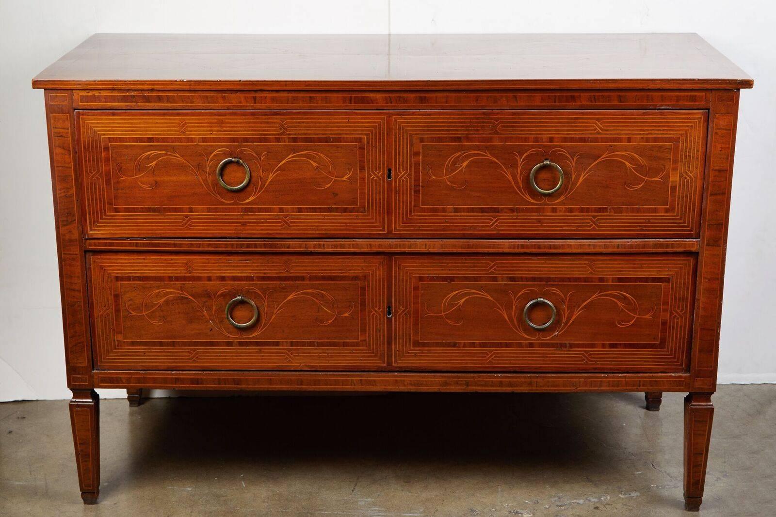Streamlined, elegant, circa 1860, Northern Italian, two-drawer walnut commode with very fine, fruitwood inlay featuring both geometric faux paneling and organic motifs throughout. The whole on tapered legs.
