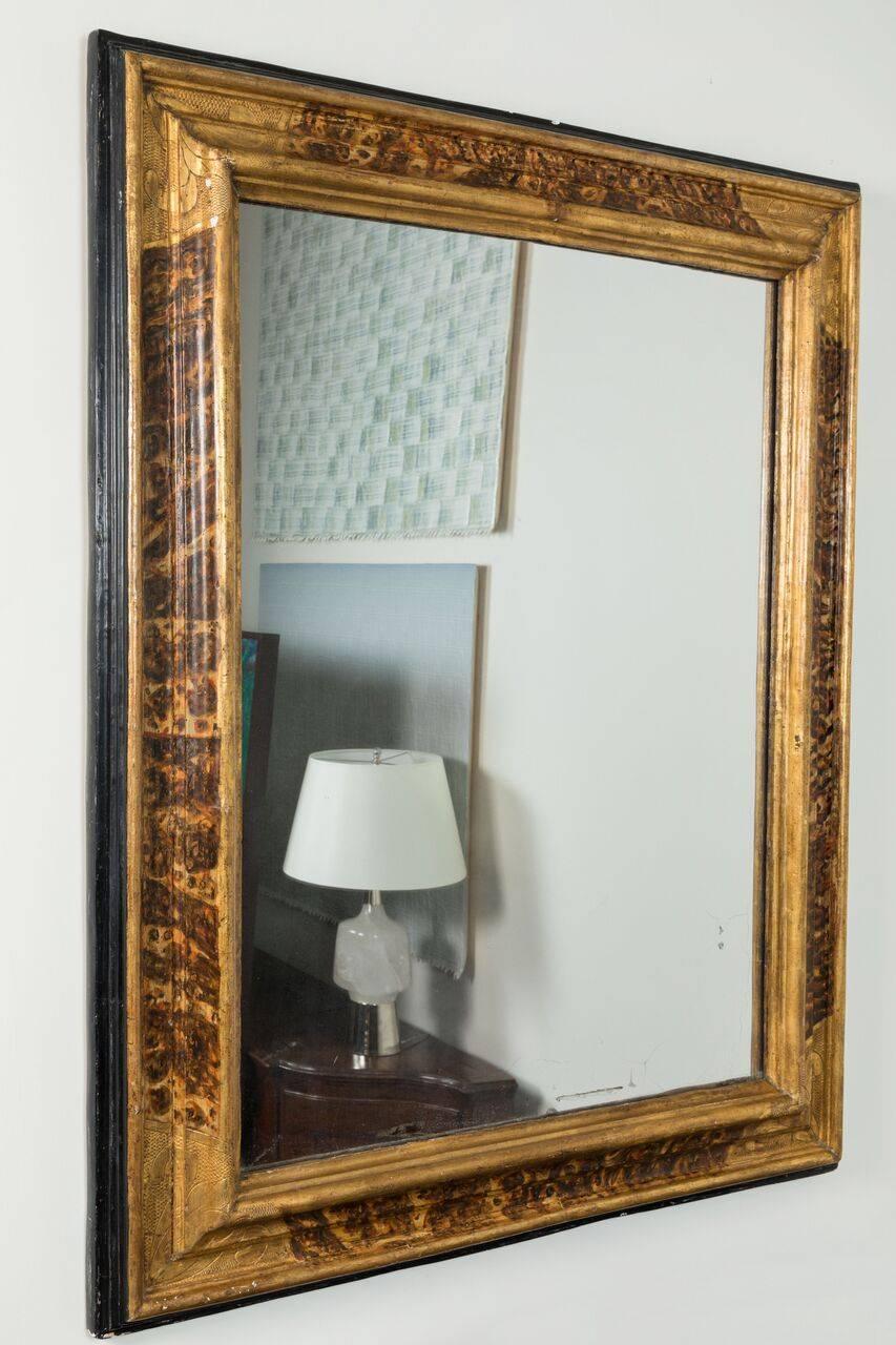 Large, continental, faux-marbled, relief carved, parcel-gilt frame with ebonized edge. The whole inset with a mercury glass mirror of a later date.