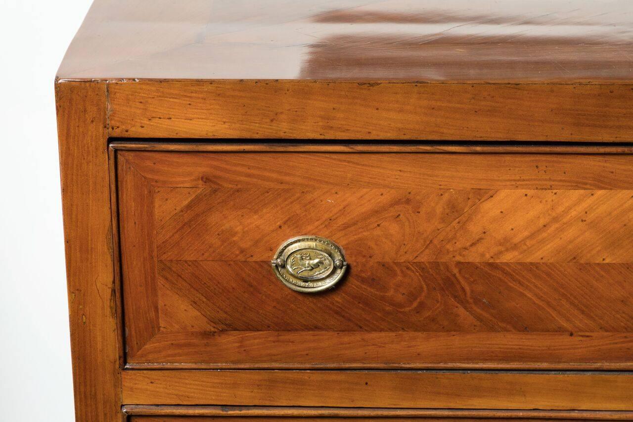 Two-drawer, tapered leg, neoclassical style, flawlessly veneered, walnut commode from Genoa, Italy. The piece features gilt bronze escutcheons with beautiful reliefs of a horned stag.