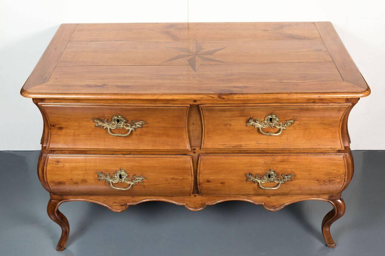 Striking, four drawer, serpentine, Bombay style, French Provencale commode in walnut. Sides embellished with faux, drawer panels. The top features a marquetry star in alternating shades. The whole on deeply bowed, cabriole legs.