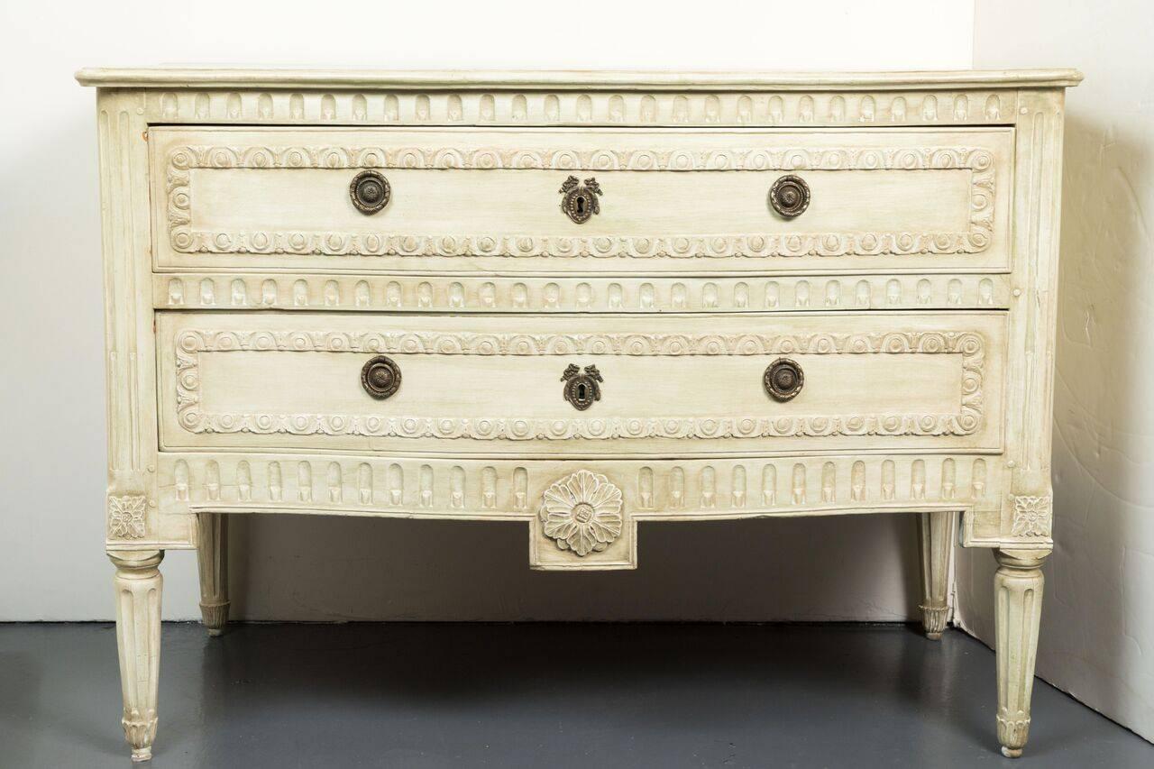 Hand-painted and hand-carved, 19th century, two-drawer, serpentine front, Louis XV style commode in creme. The whole atop a relief carved apron with central medallion and fluted, tapered legs.
