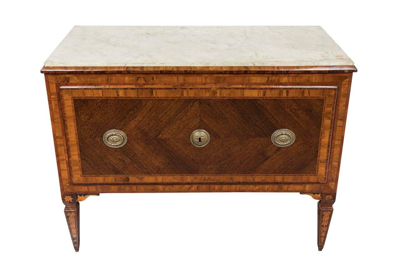 Two, hand-carved walnut, veneered, single-drawer commodes with raised side panels surmounted by beveled edges inset with white, Carrara marble tops. Each above beautifully inlaid, ebonized, tapered legs.