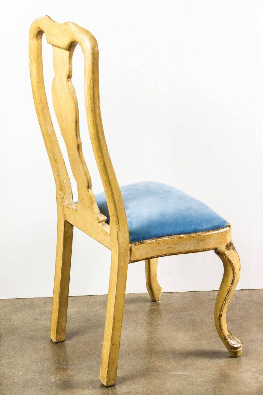 Striking set of hand-painted, parcel-gilt, circa 1930, Venetian dining chairs with forward cabriole legs and a scrolling apron. Sky blue velvet seats.