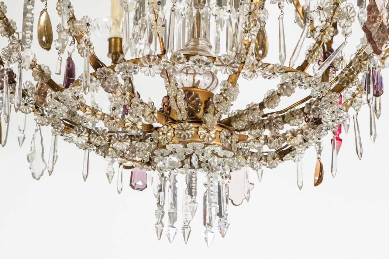 Nine light, gilt bronze and cut crystal chandelier featuring colored drops in vibrant pink, lavender, purple and smokey brown.