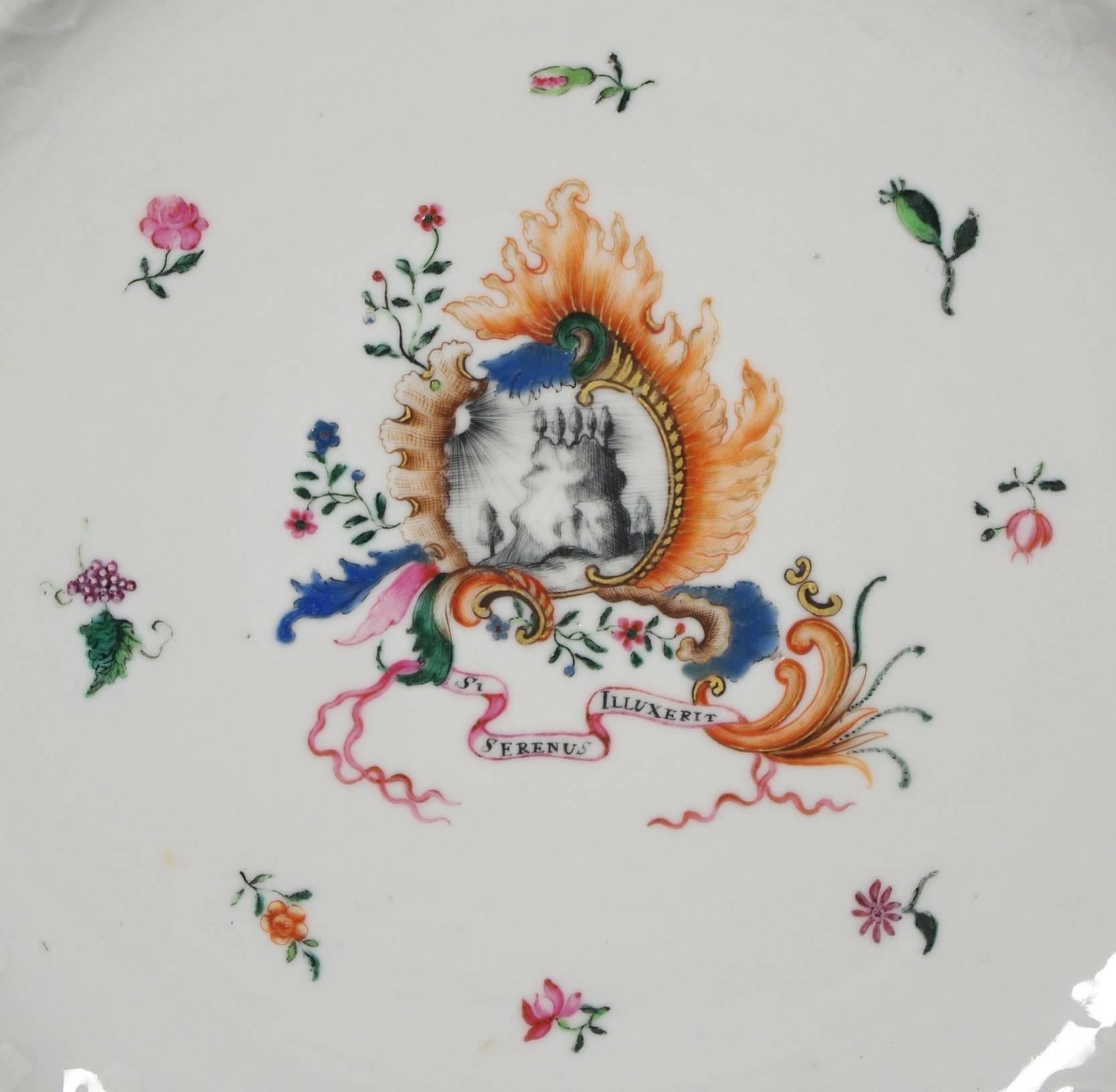 Chinese Export pseudo armorial charger, the border and cavetto with elaborate molded decoration and overglaze flower painting; the pseudo armorial with a mountain bathed in sunlight within an elaborate cartouche over the motto 