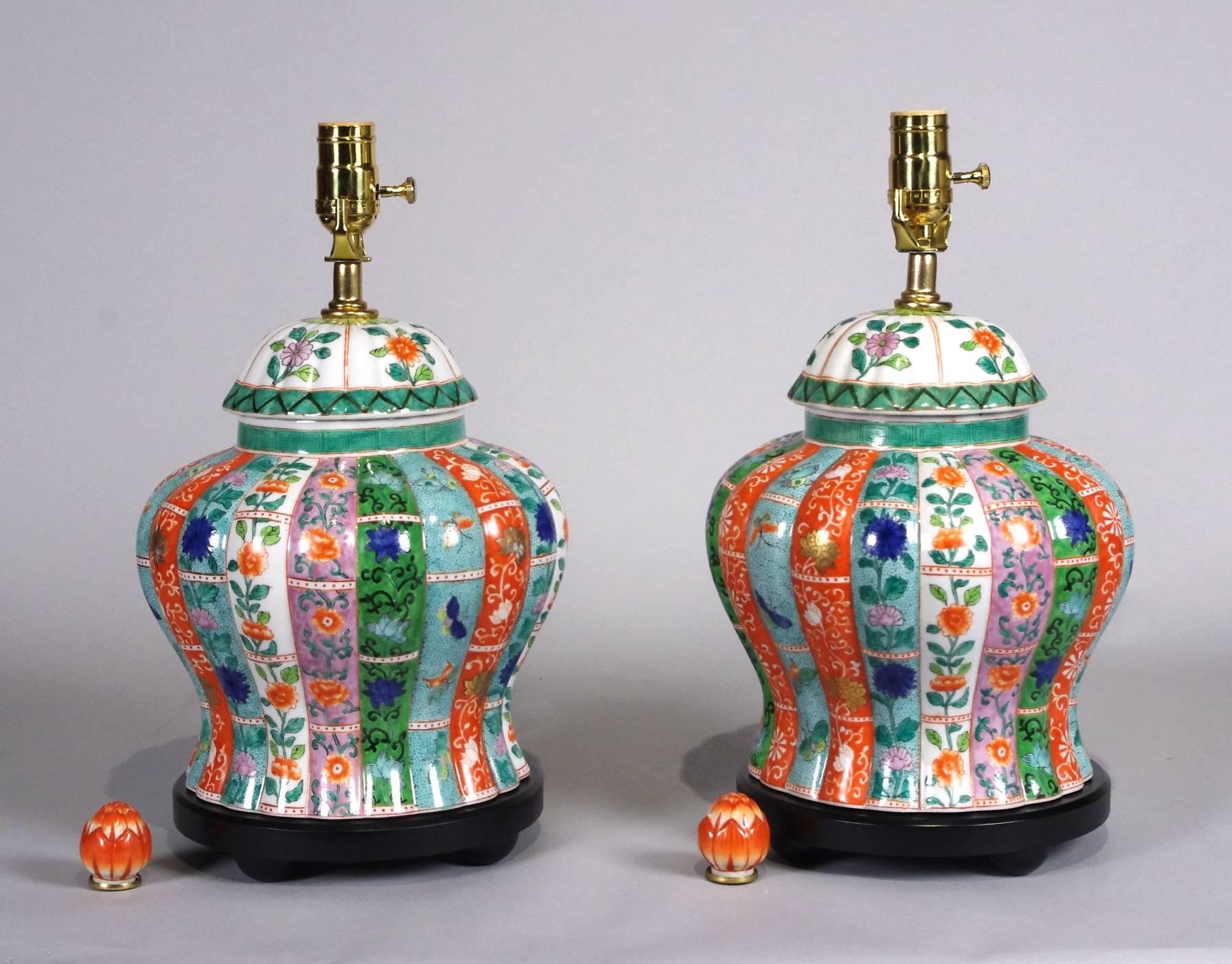 Pair of Chinese porcelain polychrome ginger jars mounted as lamps, each molded as bamboo and colorfully painted in shades of orange, green, blue, turquoise and lavender, with artichoke finials.

Lamps are 12