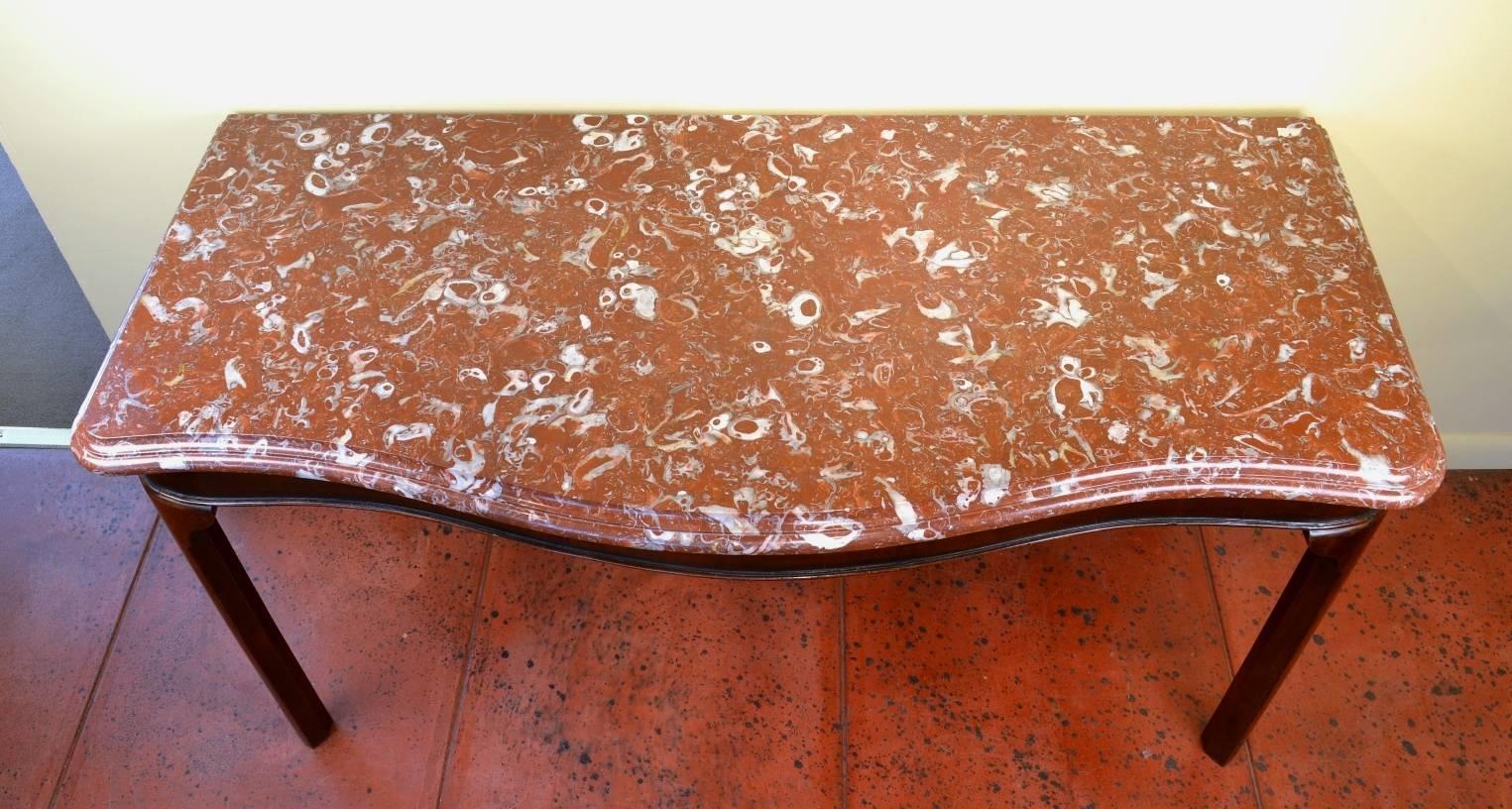 George III mahogany serpentine serving table, the red marble top (Bilbao Conchiferous) over the beaded apron supported by four square legs, each with a rounded face and ogee brackets. (Marble replaced).