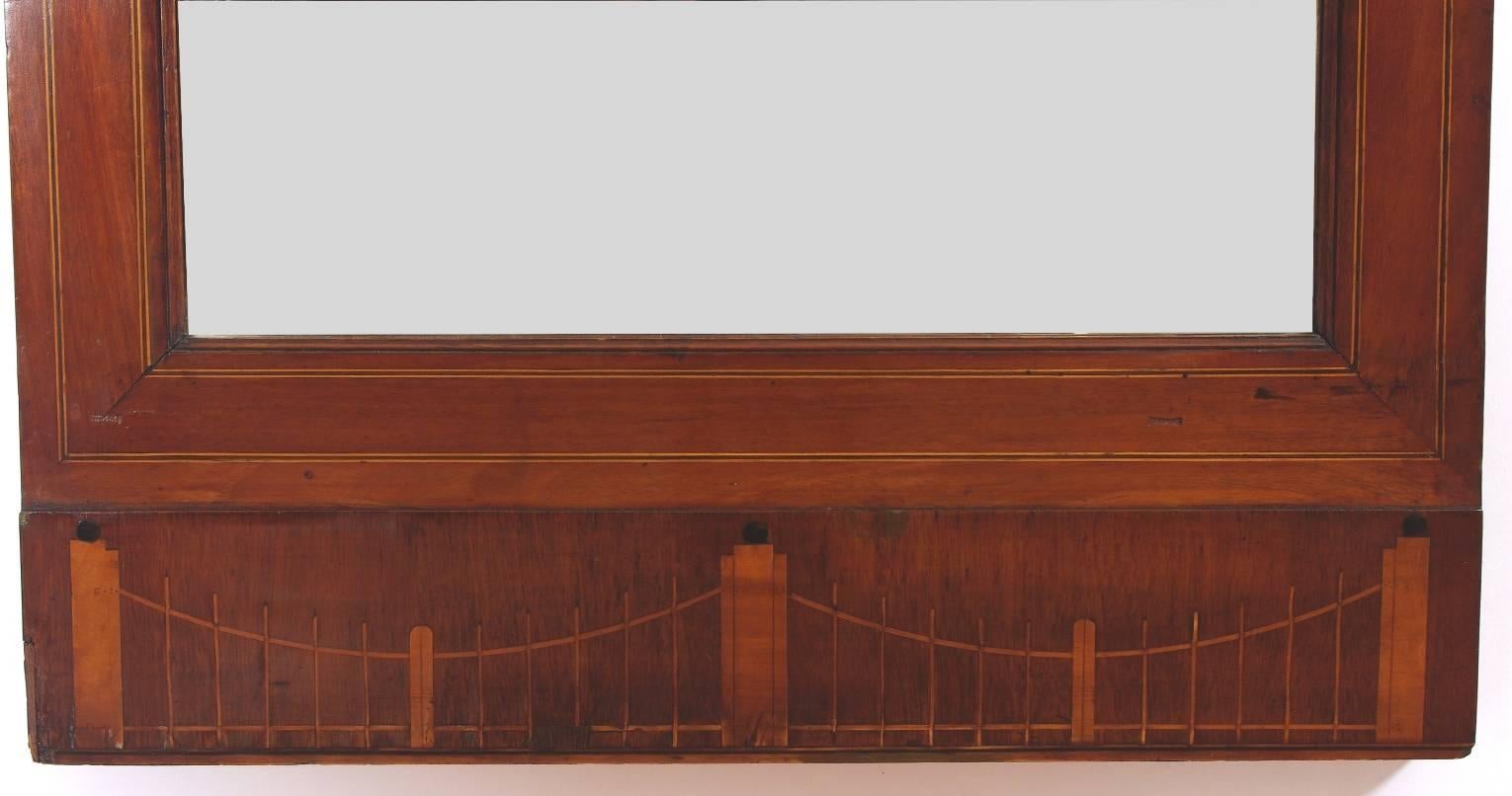 Biedermeier mahogany pier mirror, the crest with an inlaid fan on a molded cornice; the upper glass with a stylized caduceus motif over the lower frame with string inlay; the plinth with an elaborately inlaid fence and post design.

This