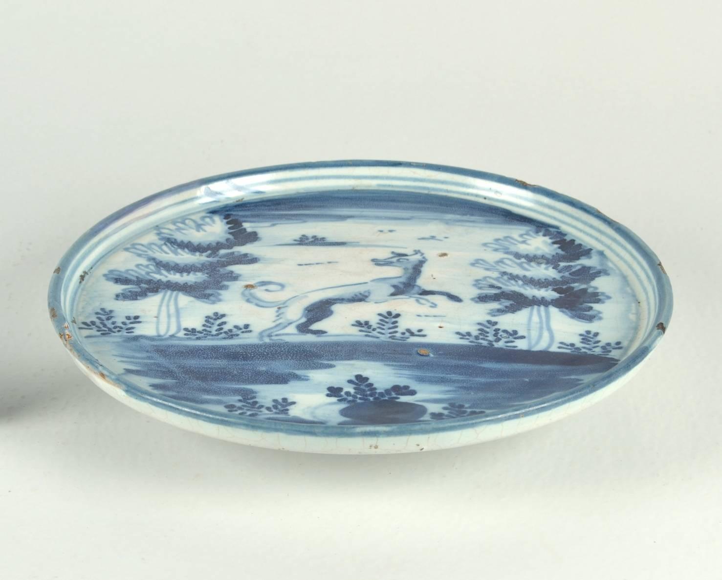 Blue and white Spanish Majolica compote (tazza) painted with a prancing creature (dog?) in a landscape with trees and shrubs.

The village of Talavera de la Reina, in present day Toledo, has been noted for its earthenware since the middle of the