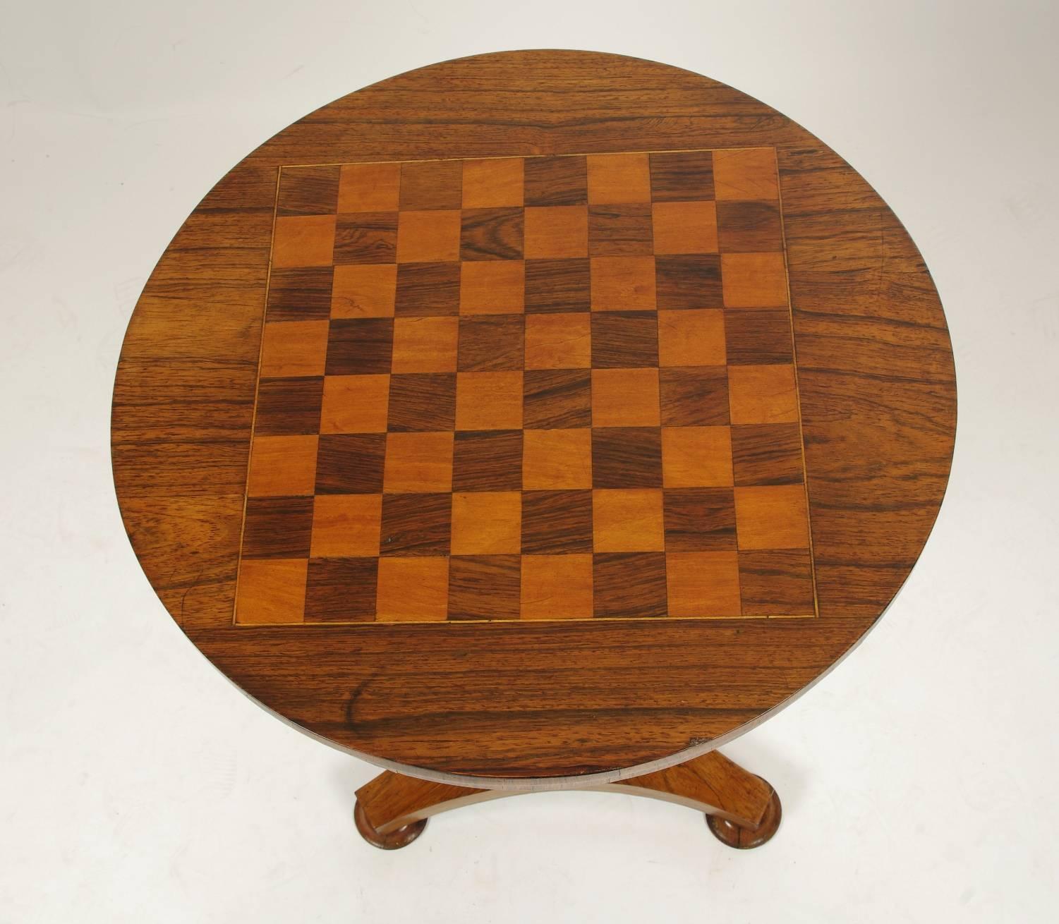 Regency rosewood games table, the round top with an inlaid chess or checker board over the short apron; the hexagonal centre post on a triangular base with turned feet.

The game board of this elegant little table is rosewood and satinwood,