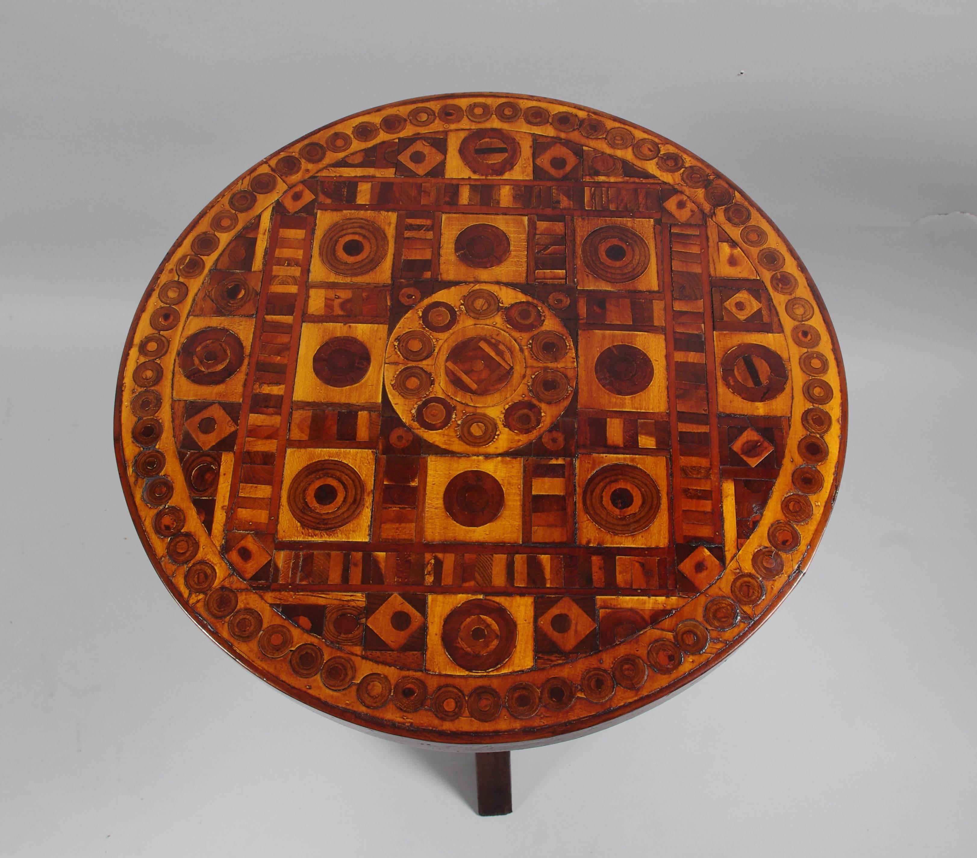 Delightful Folk Art occasional table, the circular top with elaborate geometric inlays on a center post with bullseye inlay supported by four shaped legs, each with a single small inlay to the knees.

This sturdy, exuberant table is stamped four
