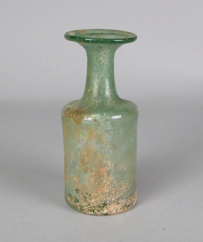 Blown in transparent pale green glass; out-splayed rim folded under; tapering neck and square shoulder; cylindrical body; pontil mark.

For a similar example, see David Woodhouse, 