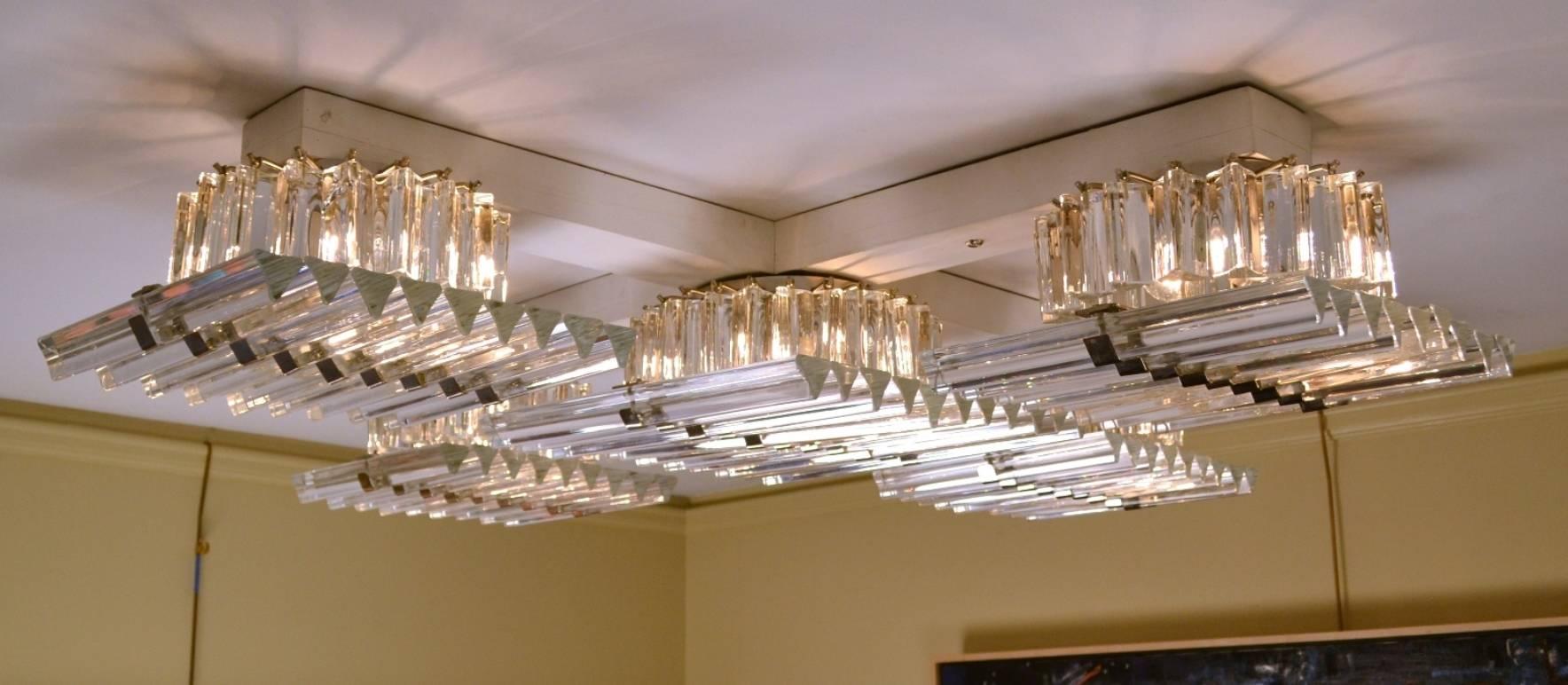 Five Murano glass light fixtures, each made from triangular canes bound together with stainless straps; the bulbs shaded by oversized prisms. These stylish lights can be grouped together to create a single large unit as shown above, or purchased