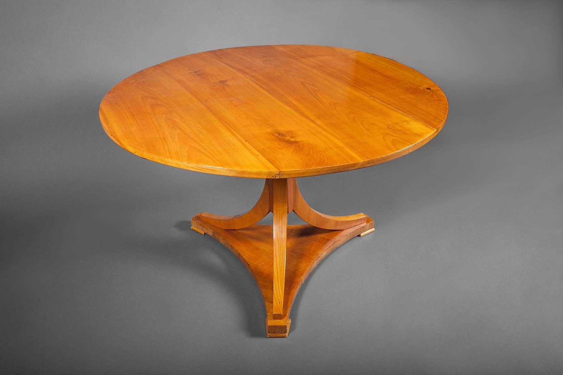 Biedermeier style fruitwood dining table with round top supported by hexagonal column on three downs wept legs standing on triangular base, second quarter of the 20th century.