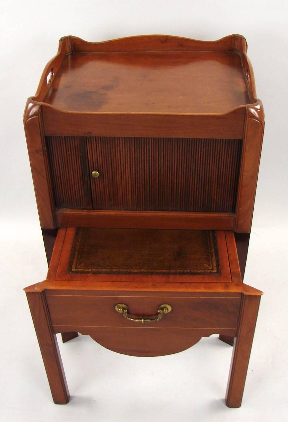 A George III mahogany bedside commode, the tray top with carrying handles above a tambour door over a slide out drawer now with a gilt-tooled leather lined surface, circa 1800.