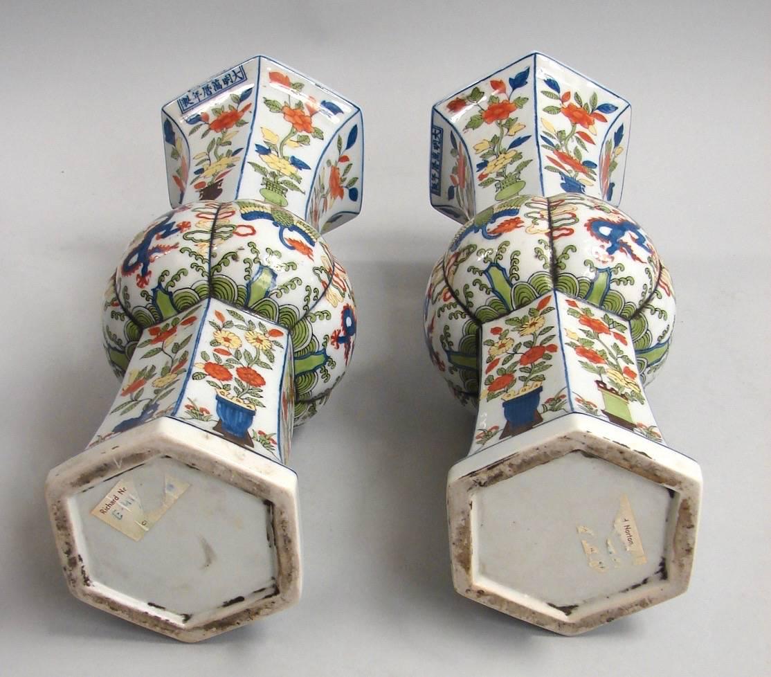 A pair of Chinese Wucai porcelain vases decorated with dragons and flowers and in tones of red blue and orange.