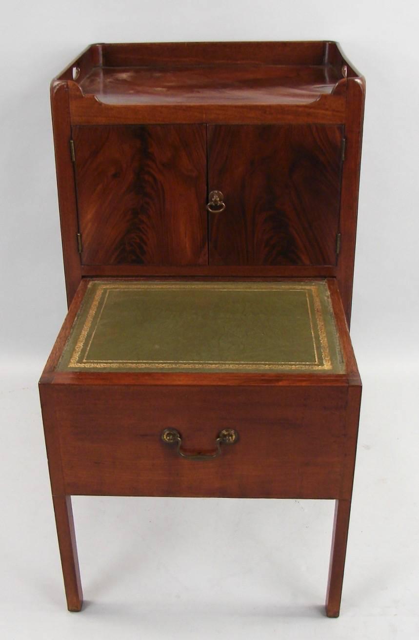 A George III mahogany bedside cabinet, the tray top with inset carry handles, above a pair of cupboard doors over a converted single drawer now modified and lined with a tooled leather surface, all supported on straight legs, circa 1800.