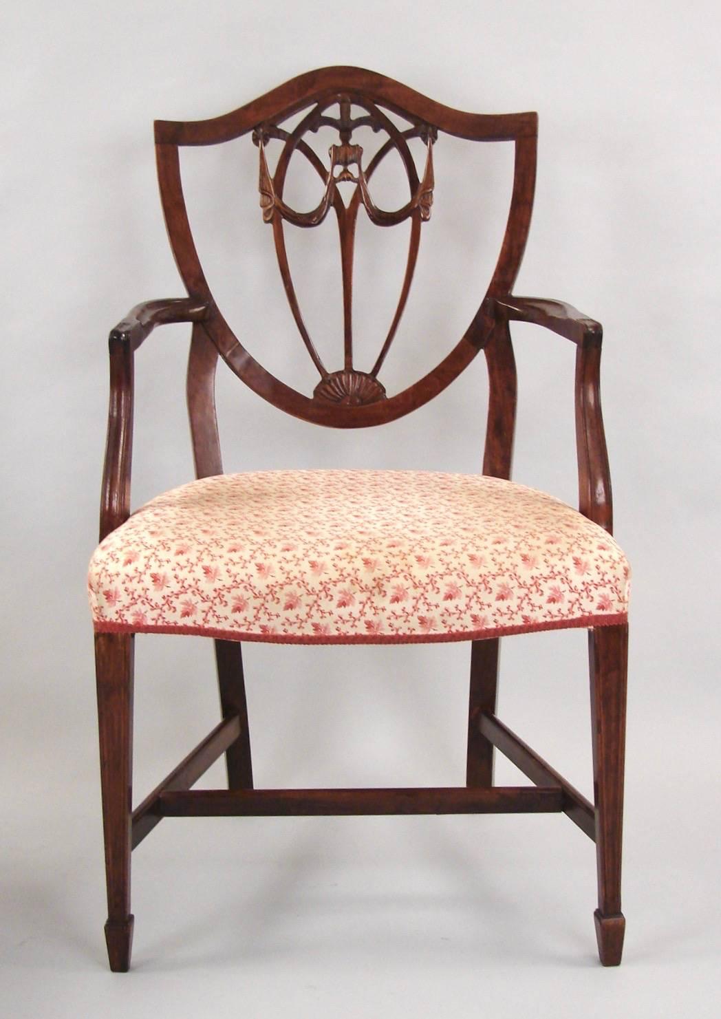 A set of eight Hepplewhite style shield back mahogany dining chairs consisting of two armchairs six side chairs each with upholstered seats, the nicely detailed back splats centered by carved Prince of Wales' feathers and swags, the serpentine seats